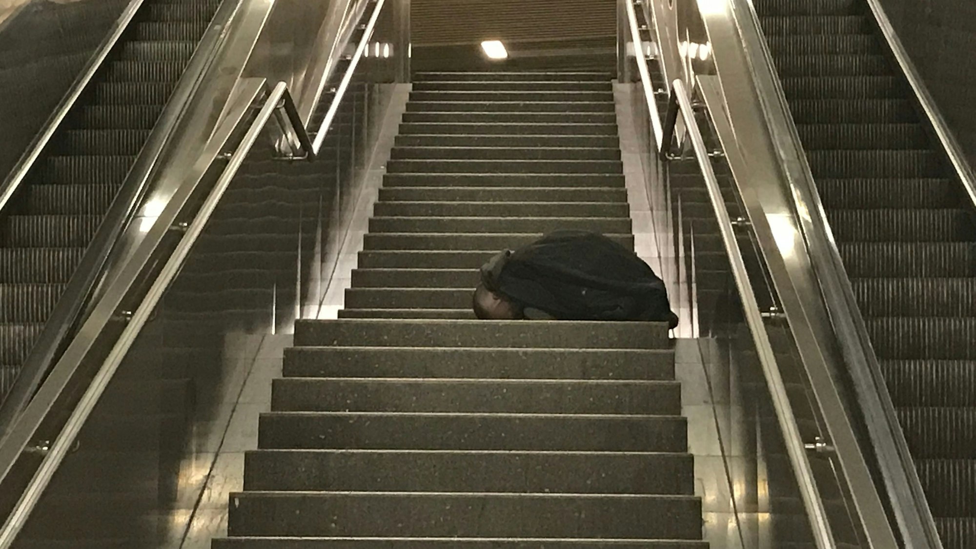 Ebenfalls an der KVB-Haltestelle Friesenplatz: Ein Obdachloser schläft auf der Treppe.