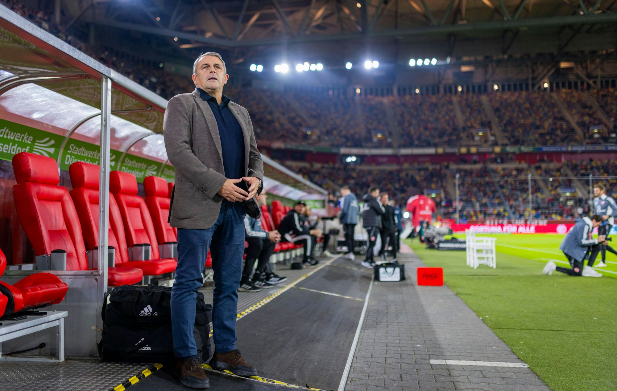 Klaus Allofs steht im Stadion vor der Trainerbank.