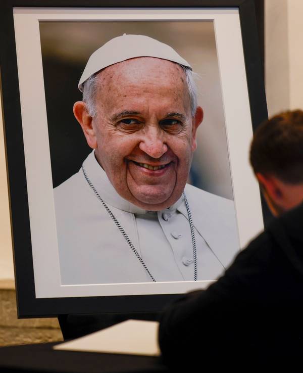 Ein Kirchenbesucher trägt sich im Bonner Münster in das Kondolenzbuch für den verstorbenen Papst Franziskus ein.