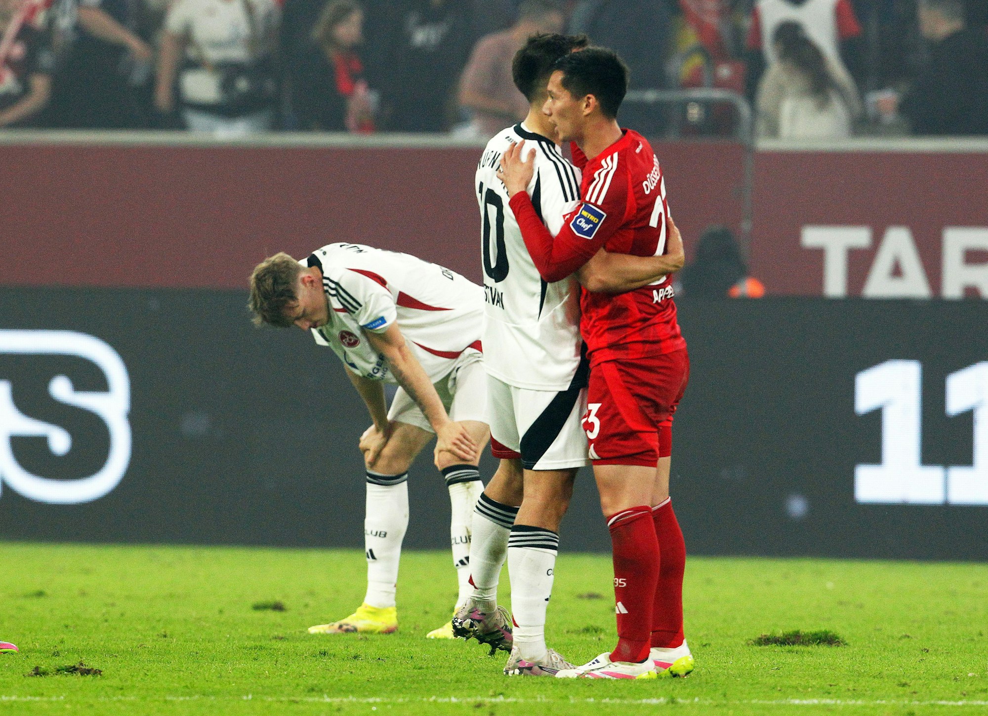 Düsseldorfs Shinta Appelkamp und Nürnbergs Spieler Caspar Jander und Julian Justvan umarmen sich nach dem Schlusspfiff.
