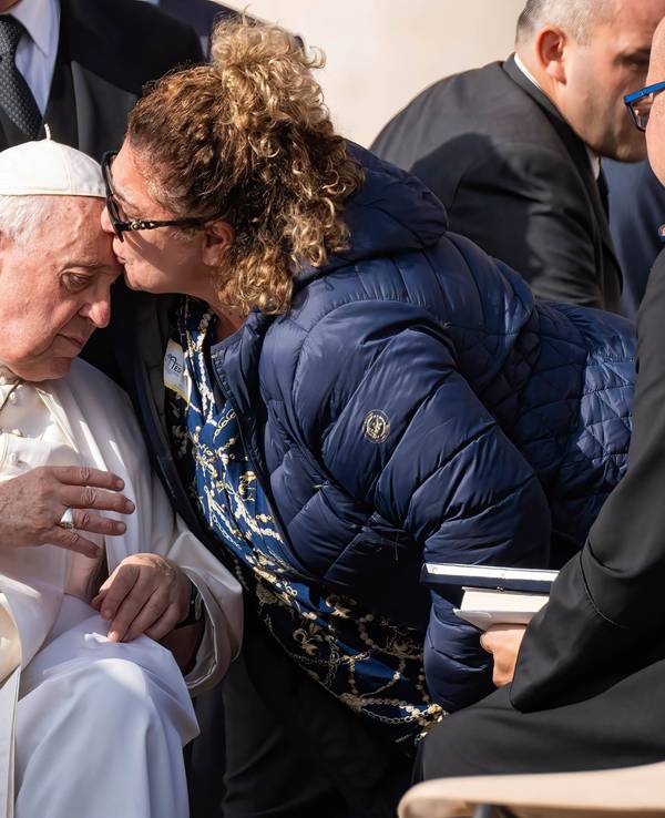 Eine Frau umarmt und küsst im Oktober 2022 Papst Franziskus.