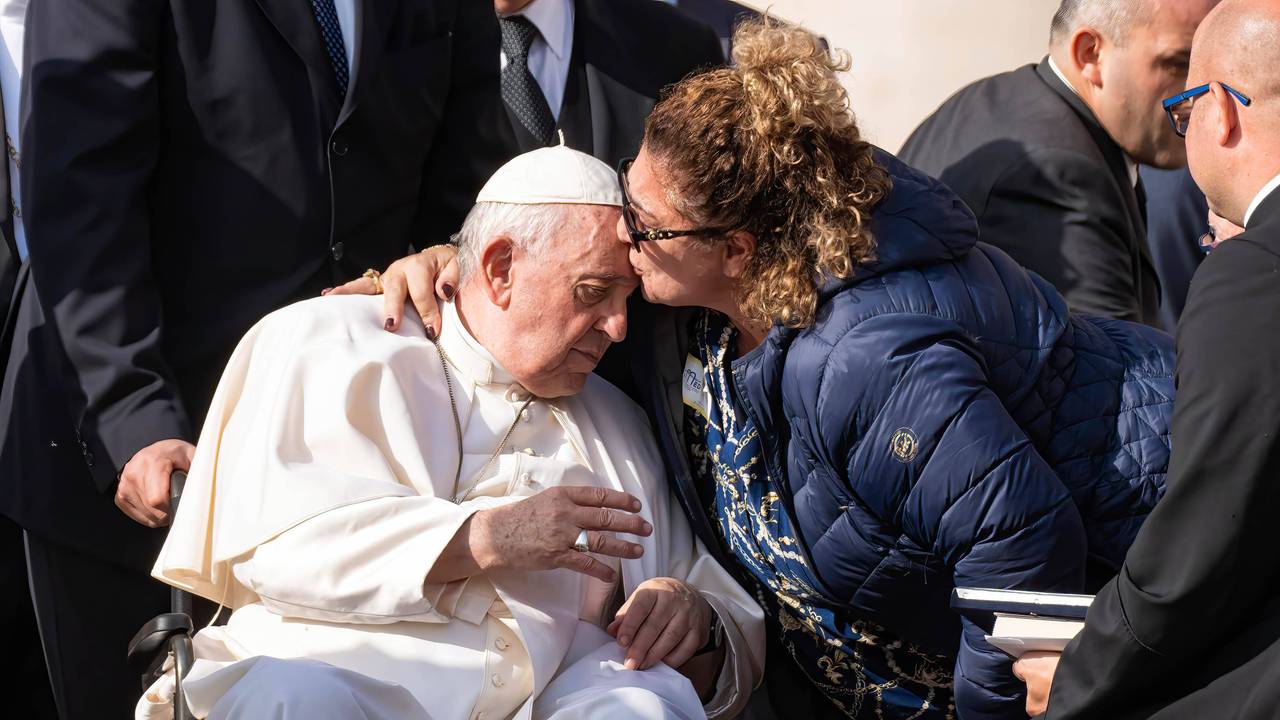 Eine Frau umarmt und küsst im Oktober 2022 Papst Franziskus.