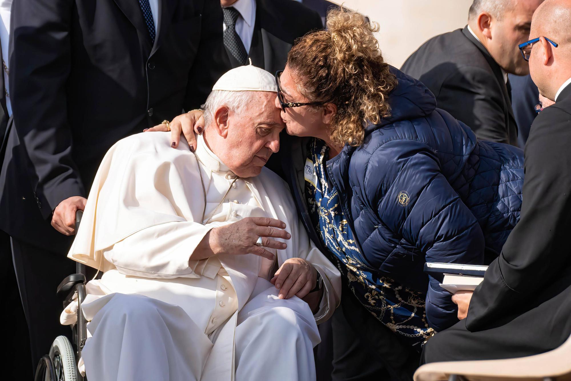 Eine Frau umarmt und küsst im Oktober 2022 Papst Franziskus.