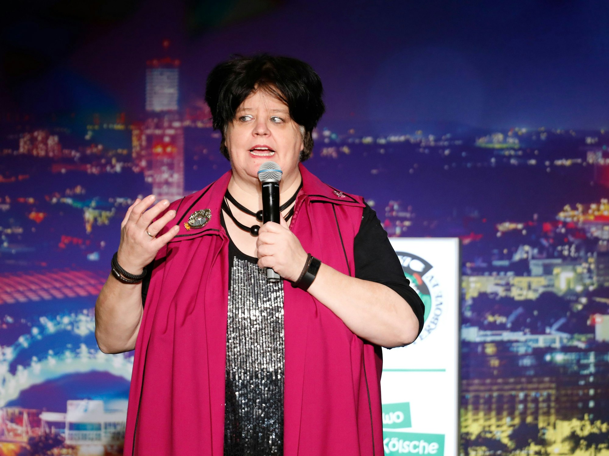 Ingrid Kühne steht mit Mikrofon auf einer Bühne.