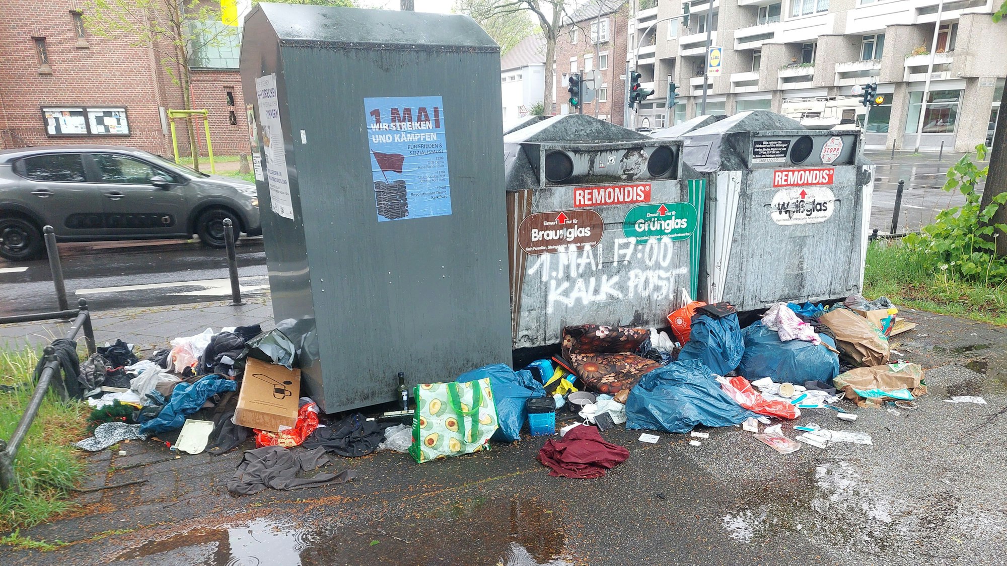 Um drei Container liegt Müll auf dem Boden.