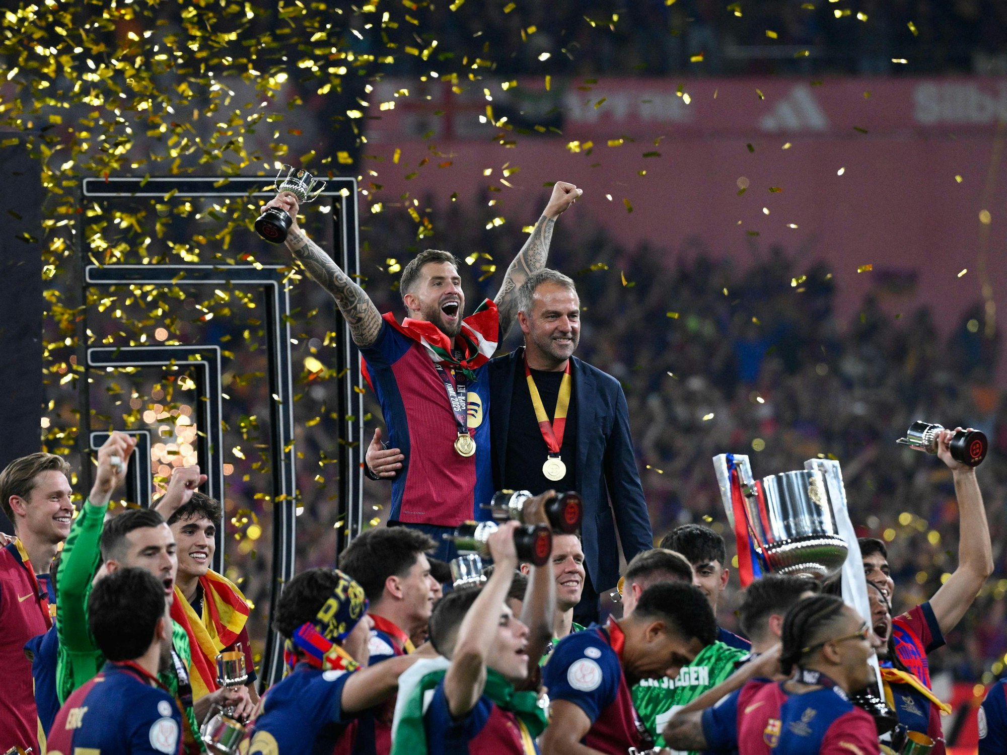 Hansi Flick (rechts) und Barcelonas Inigo Martinez Berridi bejubeln im Kreise ihrer Mannschaft den Sieg im spanischen Pokal-Finale.