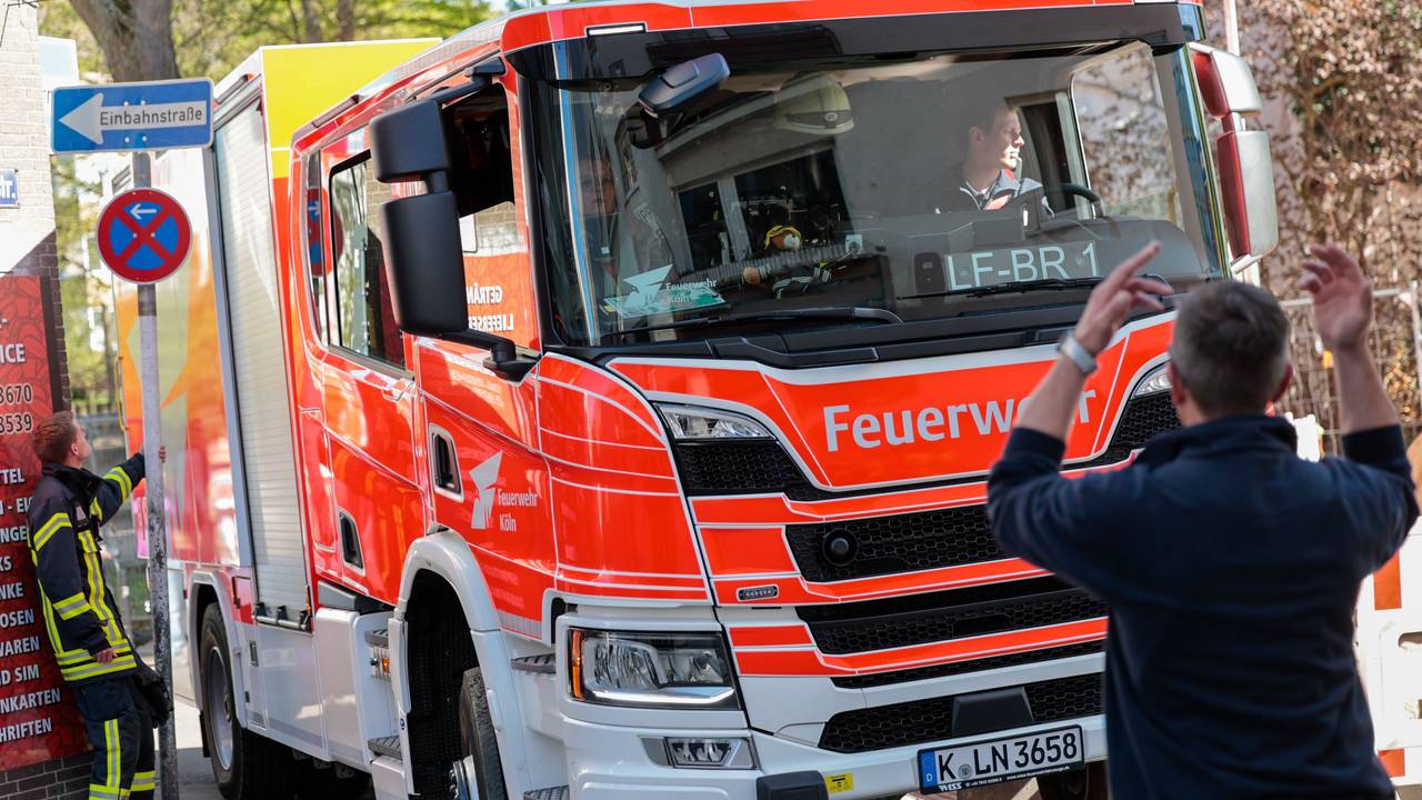 Ein Einsatzfahrzeug der Feuerwehr wird von einem Feuerwehrmann in einer engen Straße eingewiesen.