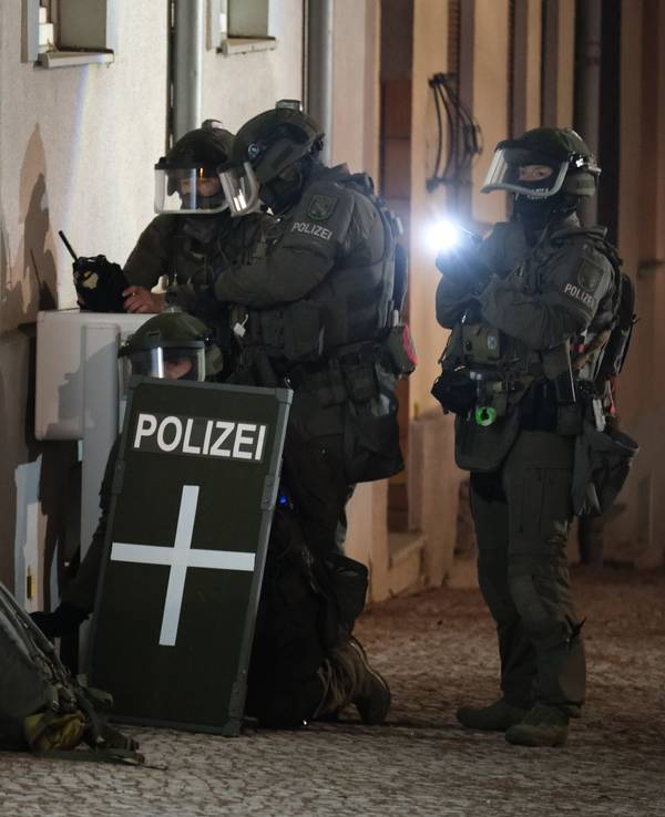 Spezialkräfte der Polizei stehen vor einem Mehrfamilienhaus.