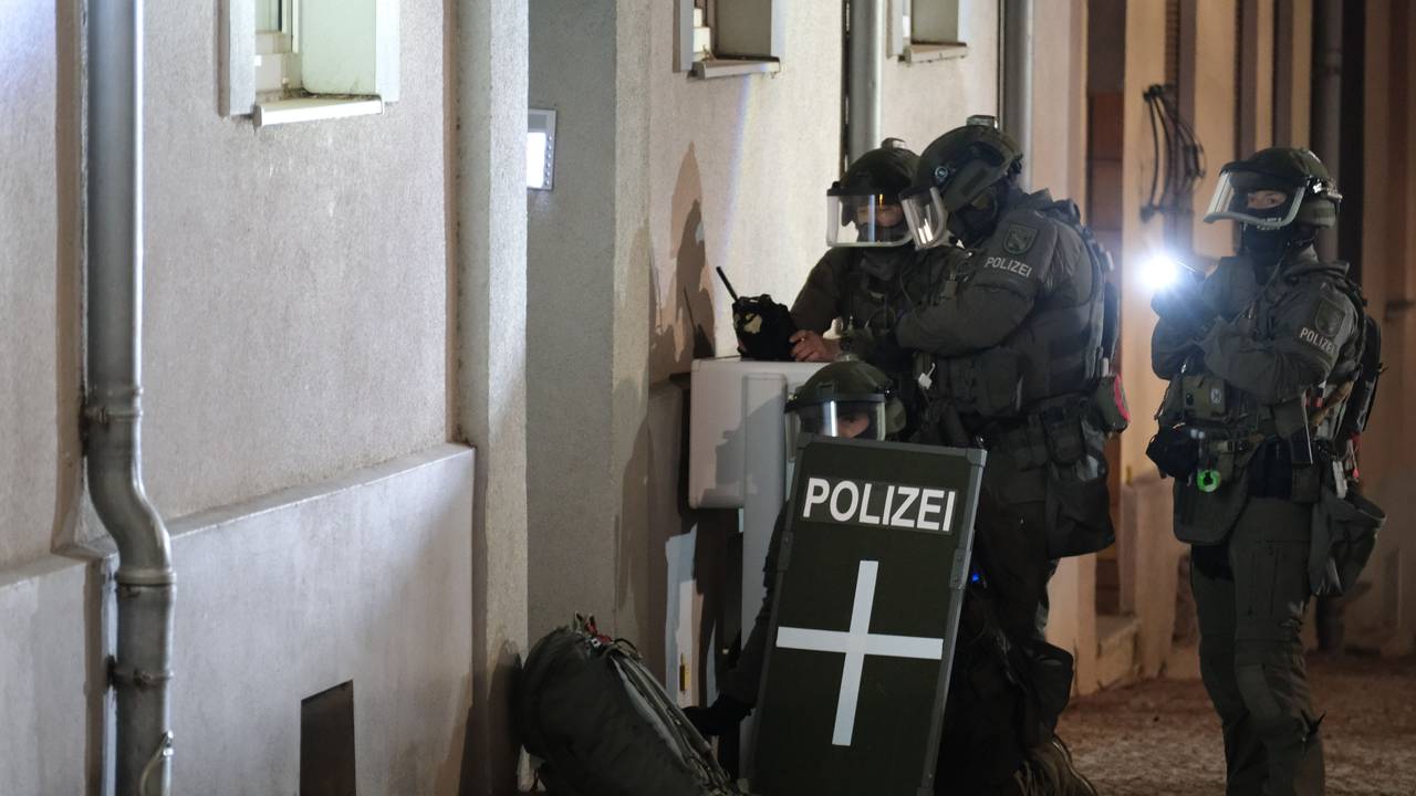 Spezialkräfte der Polizei stehen vor einem Mehrfamilienhaus.