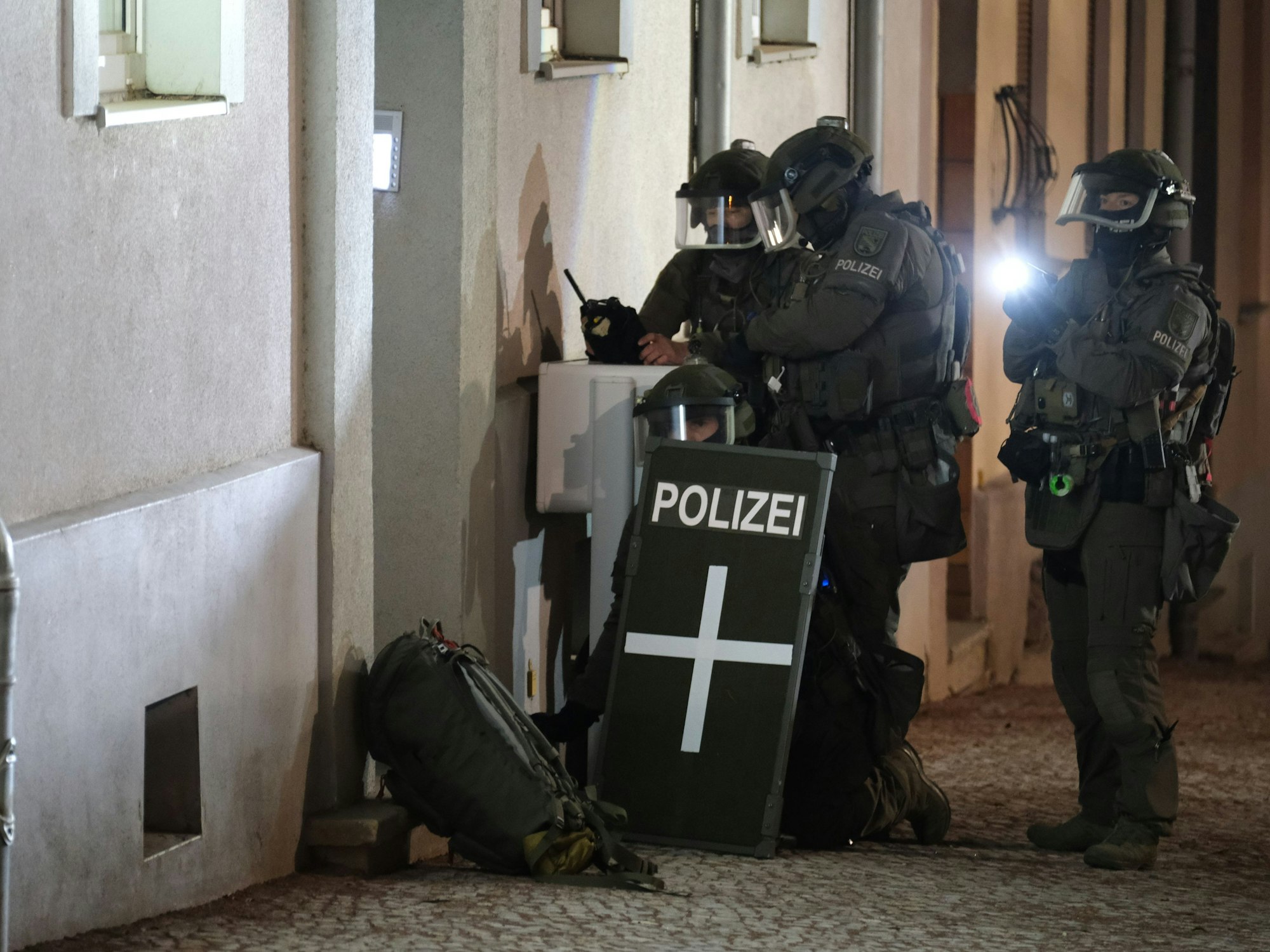 Spezialkräfte der Polizei stehen vor einem Mehrfamilienhaus.