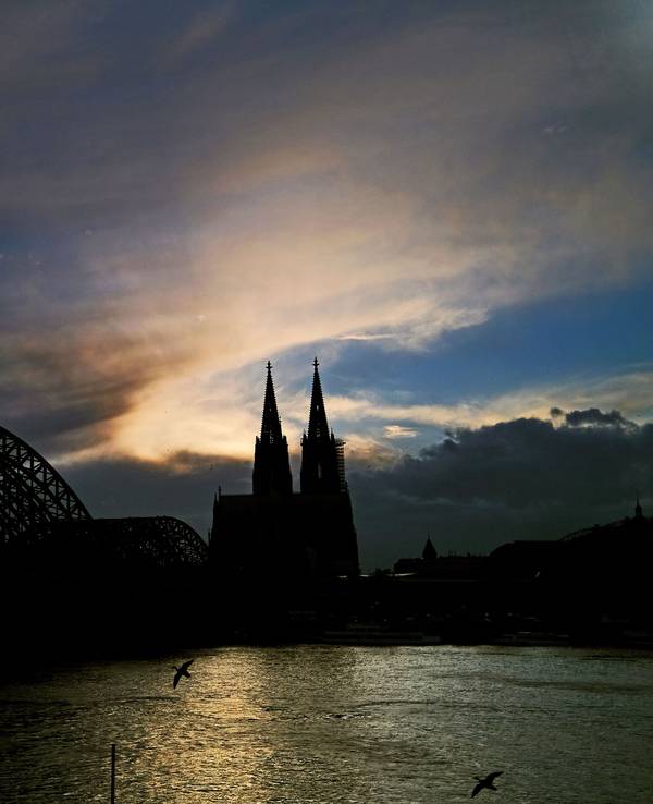 Hinter dem Dom ziehen Wolken an der untergehenden Sonne vorbei. Nach dem Mega-Blackout in Spanien und Portugal gibt die Bundesnetzagentur Entwarnung für Deutschland.