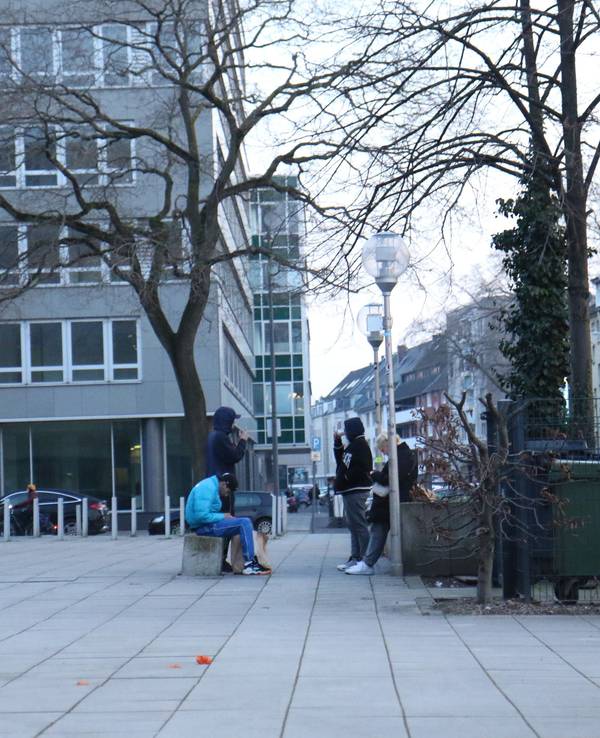 Vier Jugendliche hängen auf einem Platz ab.