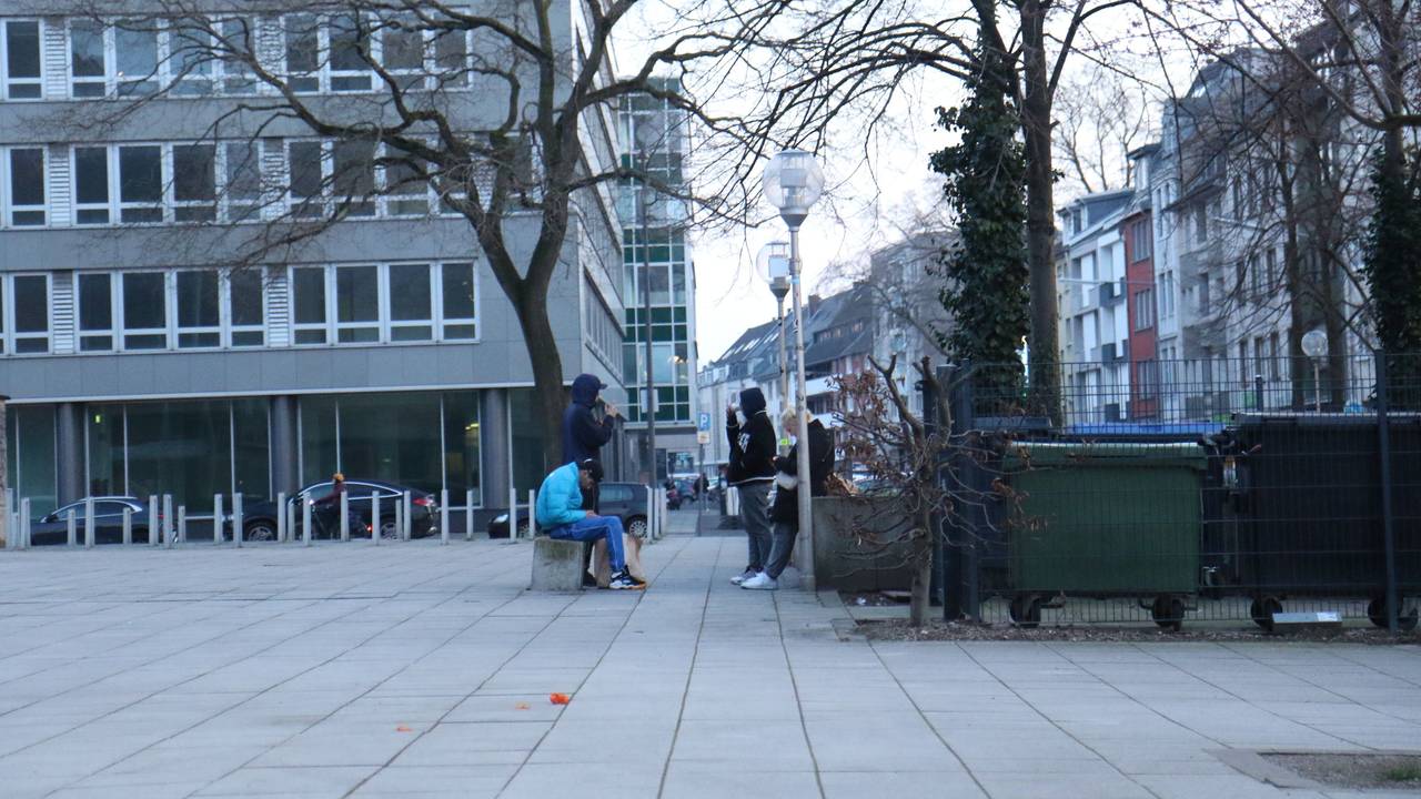 Vier Jugendliche hängen auf einem Platz ab.