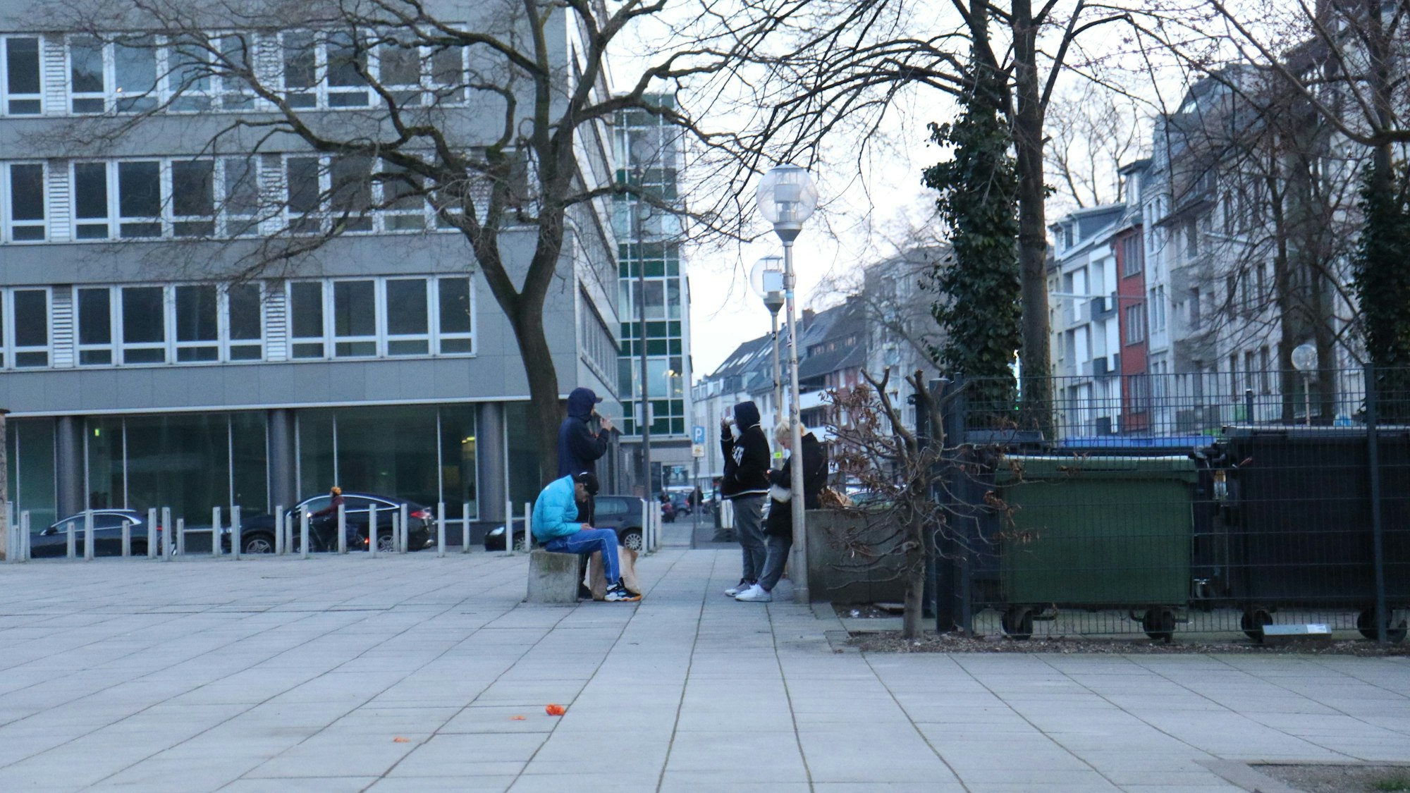 Vier Jugendliche hängen auf einem Platz ab.