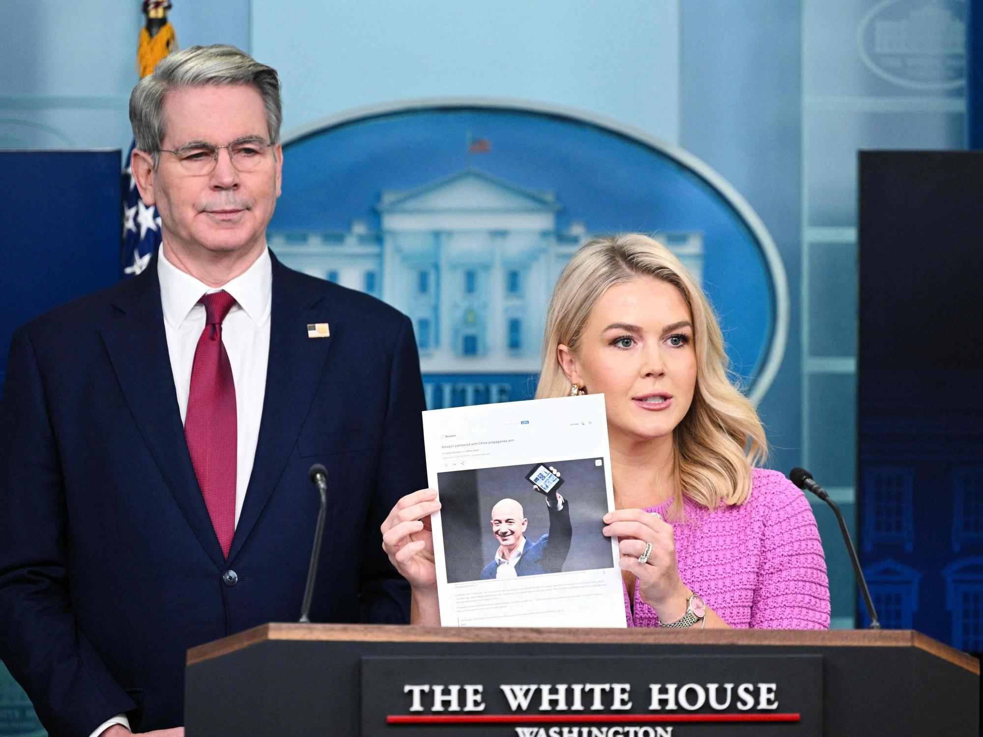 Die Pressesprecherin des Weißen Hauses, Karoline Leavitt, hält zusammen mit US-Finanzminister Scott Bessent einen Zeitungsartikel über Amazon-CEO Jeff Bezos in der Hand.