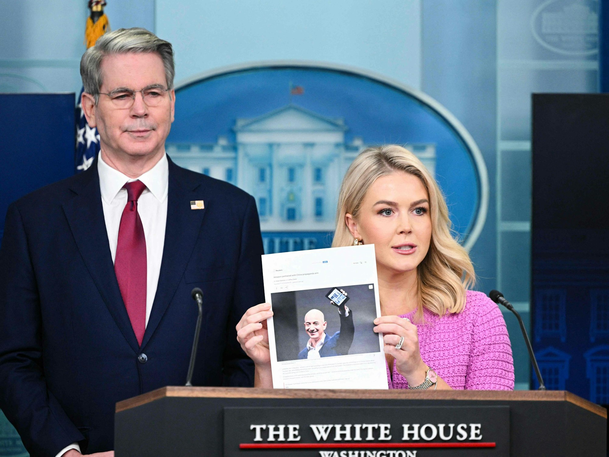 Die Pressesprecherin des Weißen Hauses, Karoline Leavitt, hält zusammen mit US-Finanzminister Scott Bessent einen Zeitungsartikel über Amazon-CEO Jeff Bezos in der Hand.