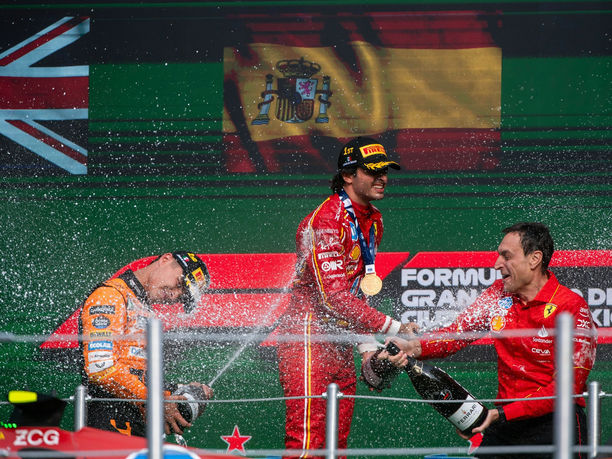 Carlos Sainz jubelt auf dem Podium und spritzt Champagner.