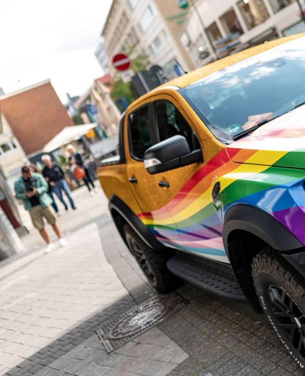 Der in Regenbogenfarben und goldenem Glitter lackierte oder folierte CSD-Raptor.