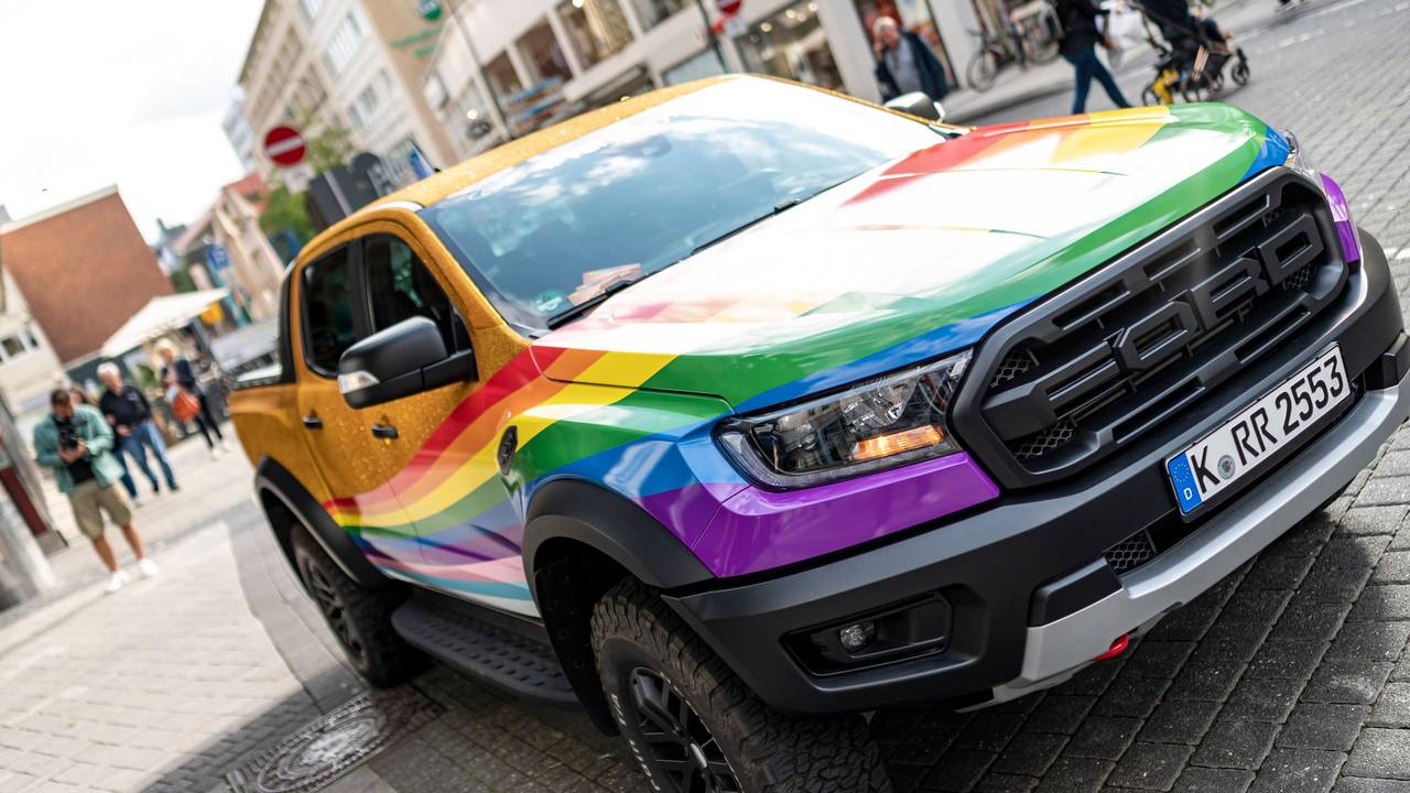 Der in Regenbogenfarben und goldenem Glitter lackierte oder folierte CSD-Raptor.