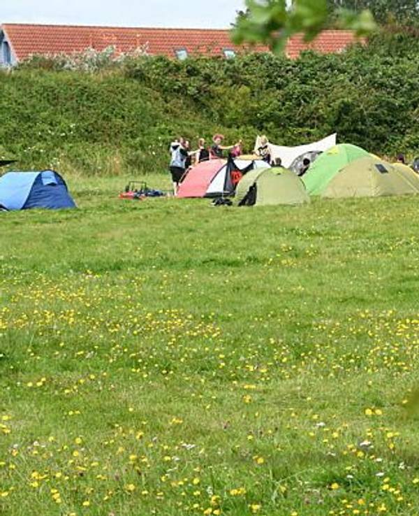 Teilnehmer des Punk-Protestcamps auf Sylt sitzen auf der Camp-Wiese von "Aktion Sylt".