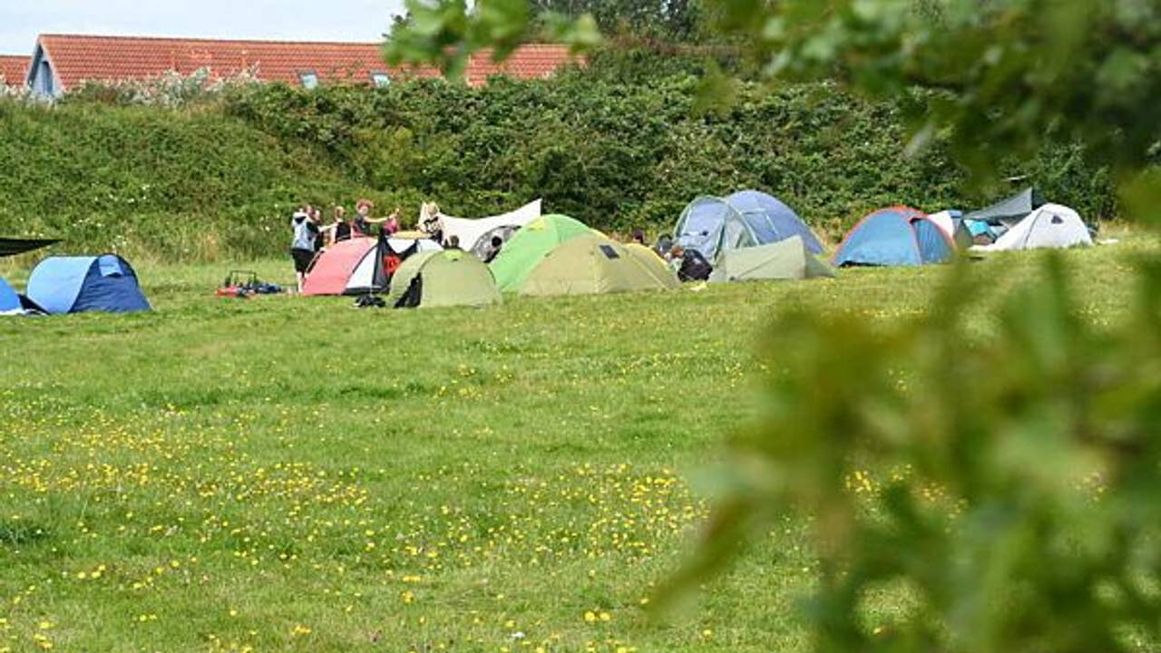Teilnehmer des Punk-Protestcamps auf Sylt sitzen auf der Camp-Wiese von "Aktion Sylt".