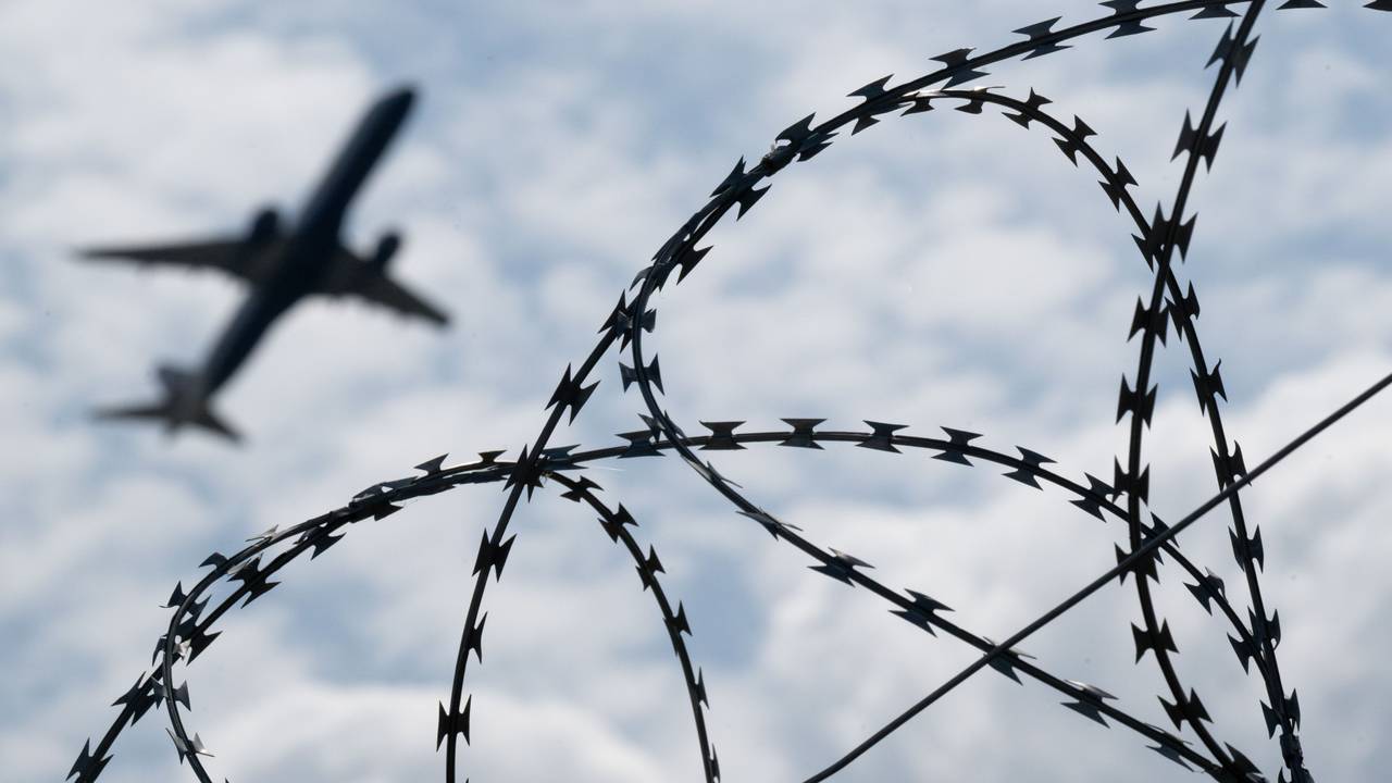 Ein Flugzeug hebt hinter einem Zaun.