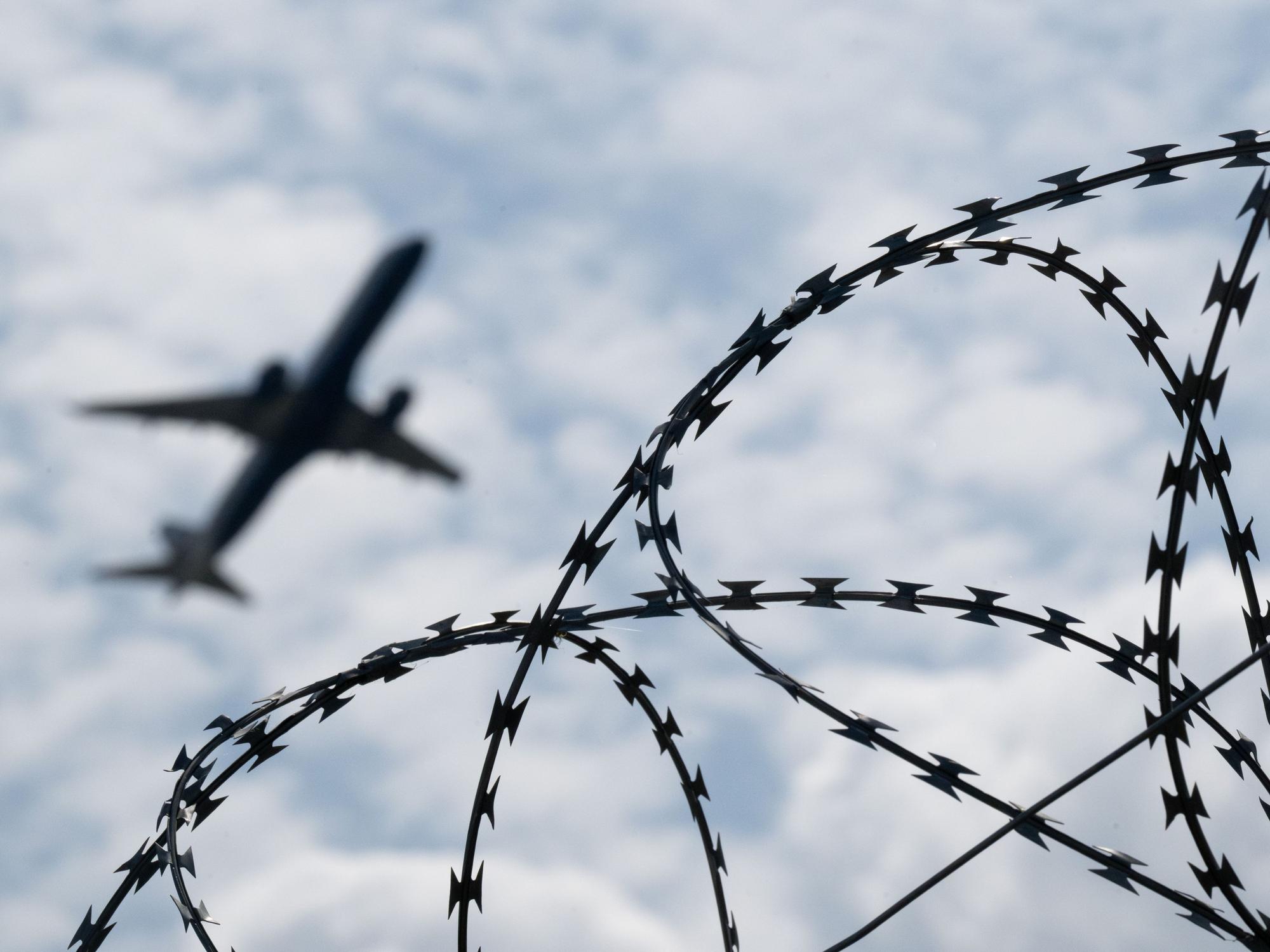 Ein Flugzeug hebt hinter einem Zaun.