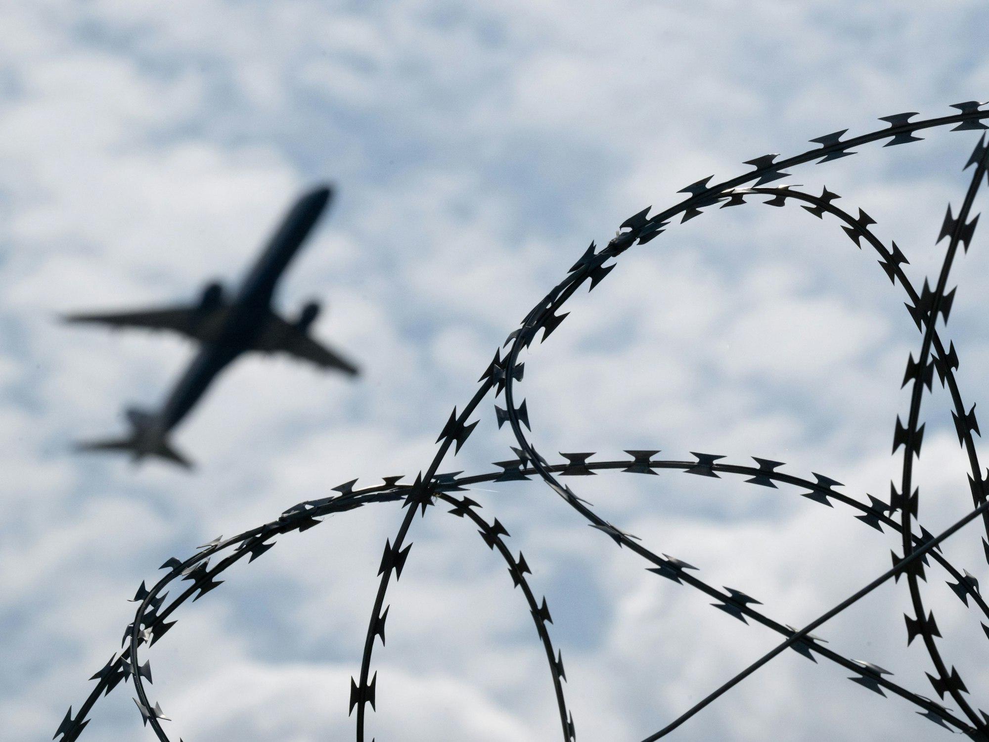 Ein Flugzeug hebt hinter einem Zaun.