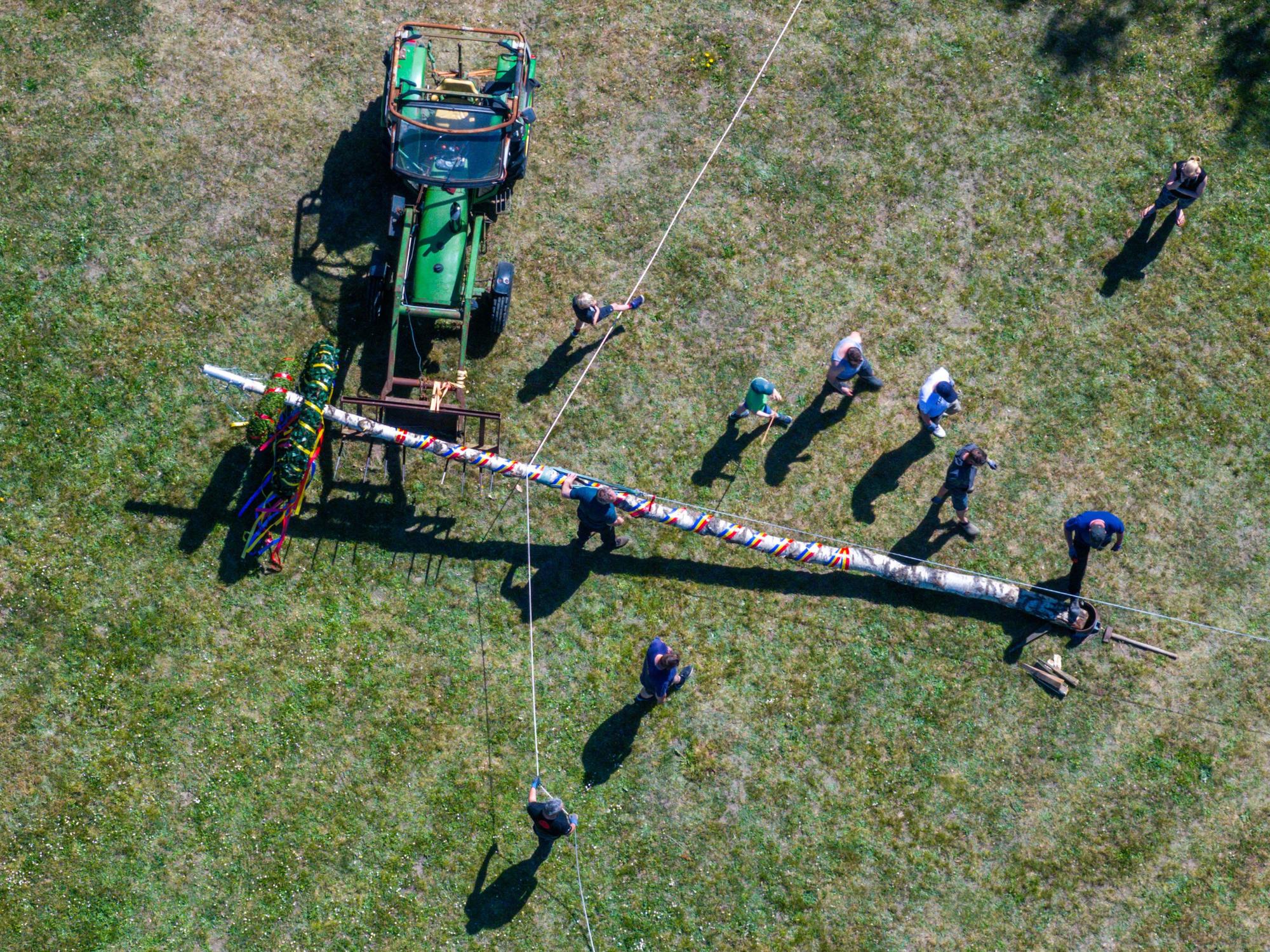 Mitglieder der Freiwilligen Feuerwehr und der Traktortruppe Pokrent (Mecklenburg-Vorpommern stellen am Dorfteich den traditionellen Maibaum auf.