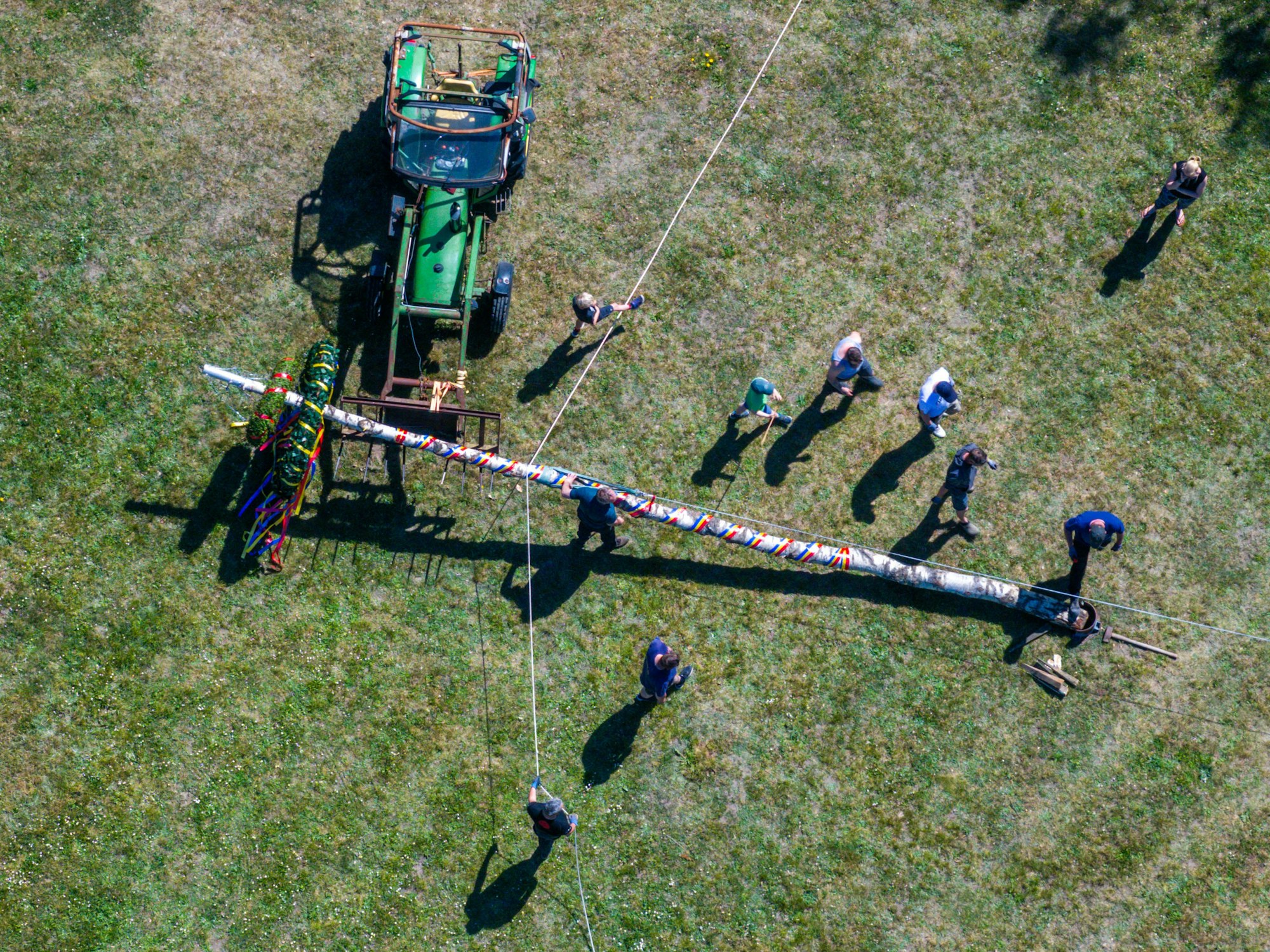 Mitglieder der Freiwilligen Feuerwehr und der Traktortruppe Pokrent (Mecklenburg-Vorpommern stellen am Dorfteich den traditionellen Maibaum auf.