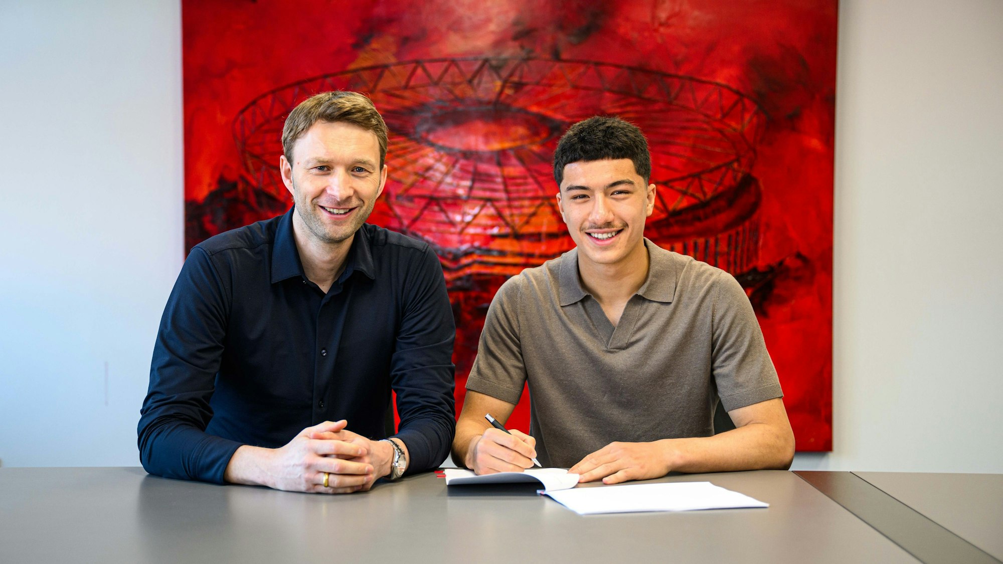 Ibrahim Maza und Simon Rolfes posieren am 1. Mai 2025 bei der Vertragsunterschrift in Leverkusen.