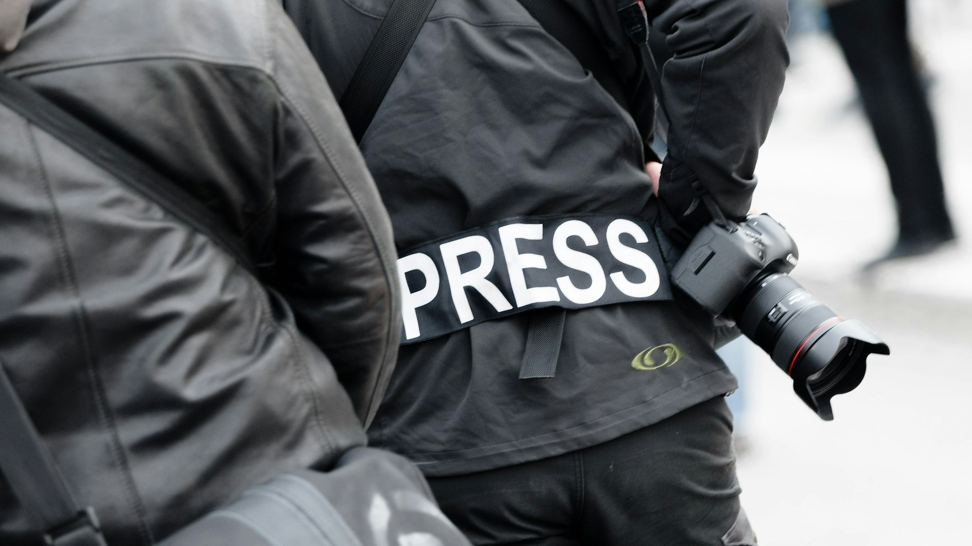 Ein Fotoreporter trägt auf einer Demonstration einen Aufnäher mit „Press“ auf seiner Jacke, um sich gegenüber Polizei und Demonstranten als Journalist zu kennzeichnen.