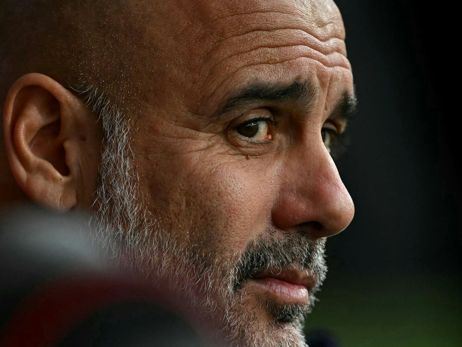 Pep Guardiola sitzt auf der Trainerbank.