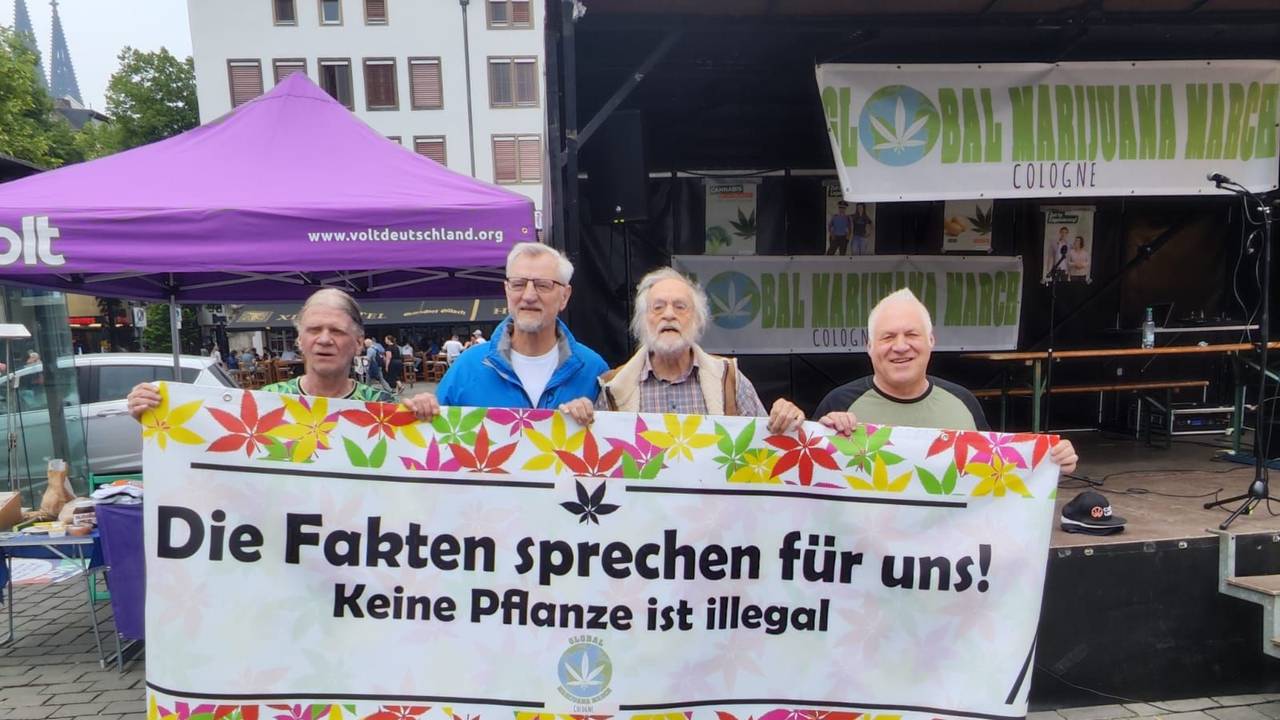 Vier Männer halten ein Plakat.