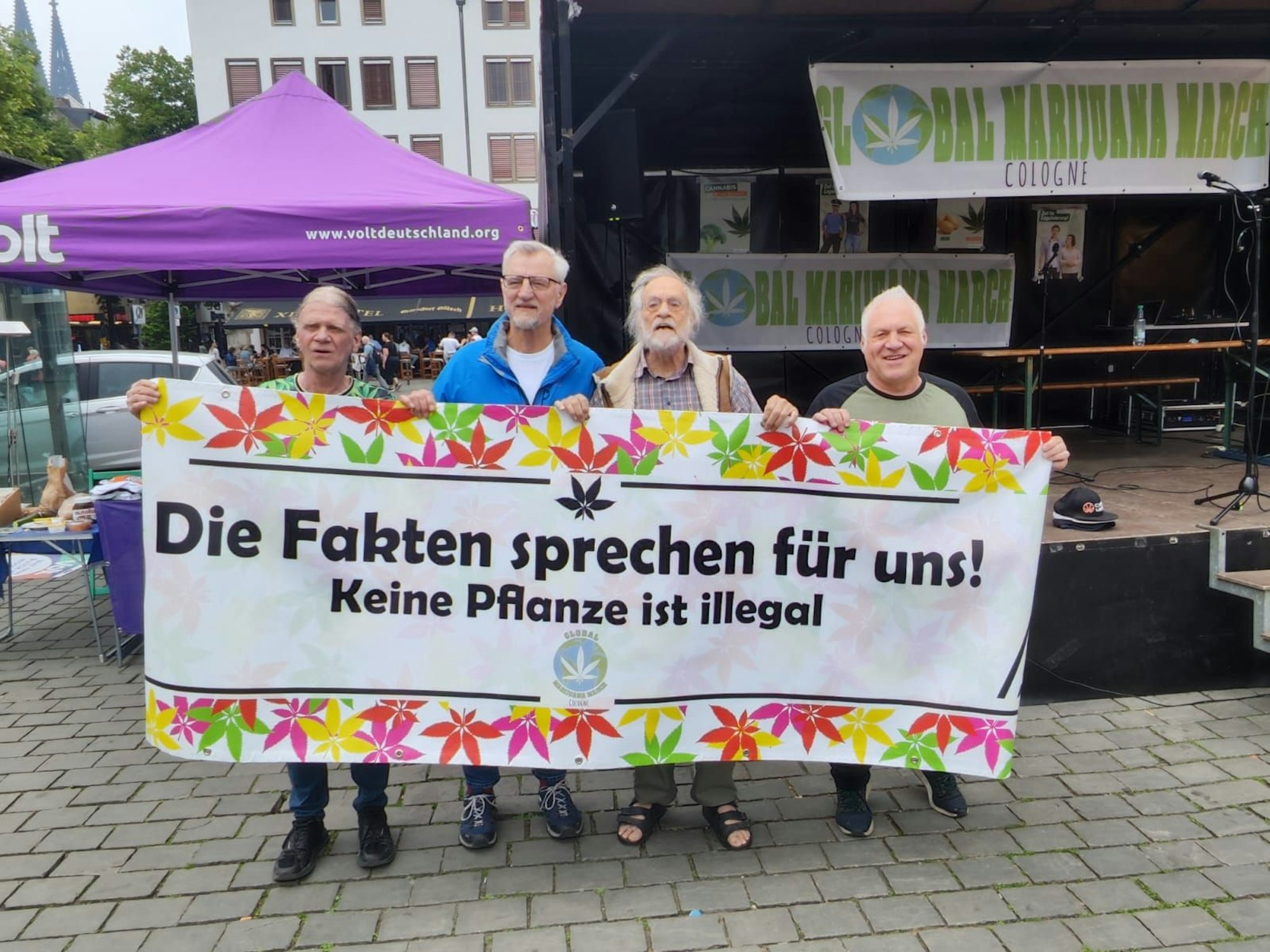 Vier Männer halten ein Plakat.