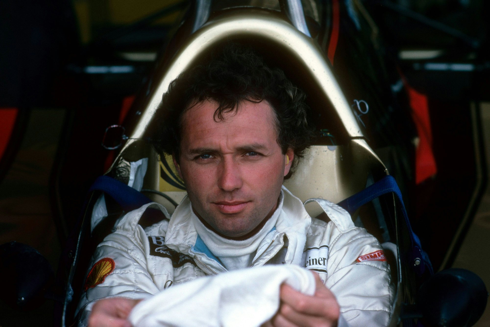 Jochen Mass sitzt in seinem Rennwagen.