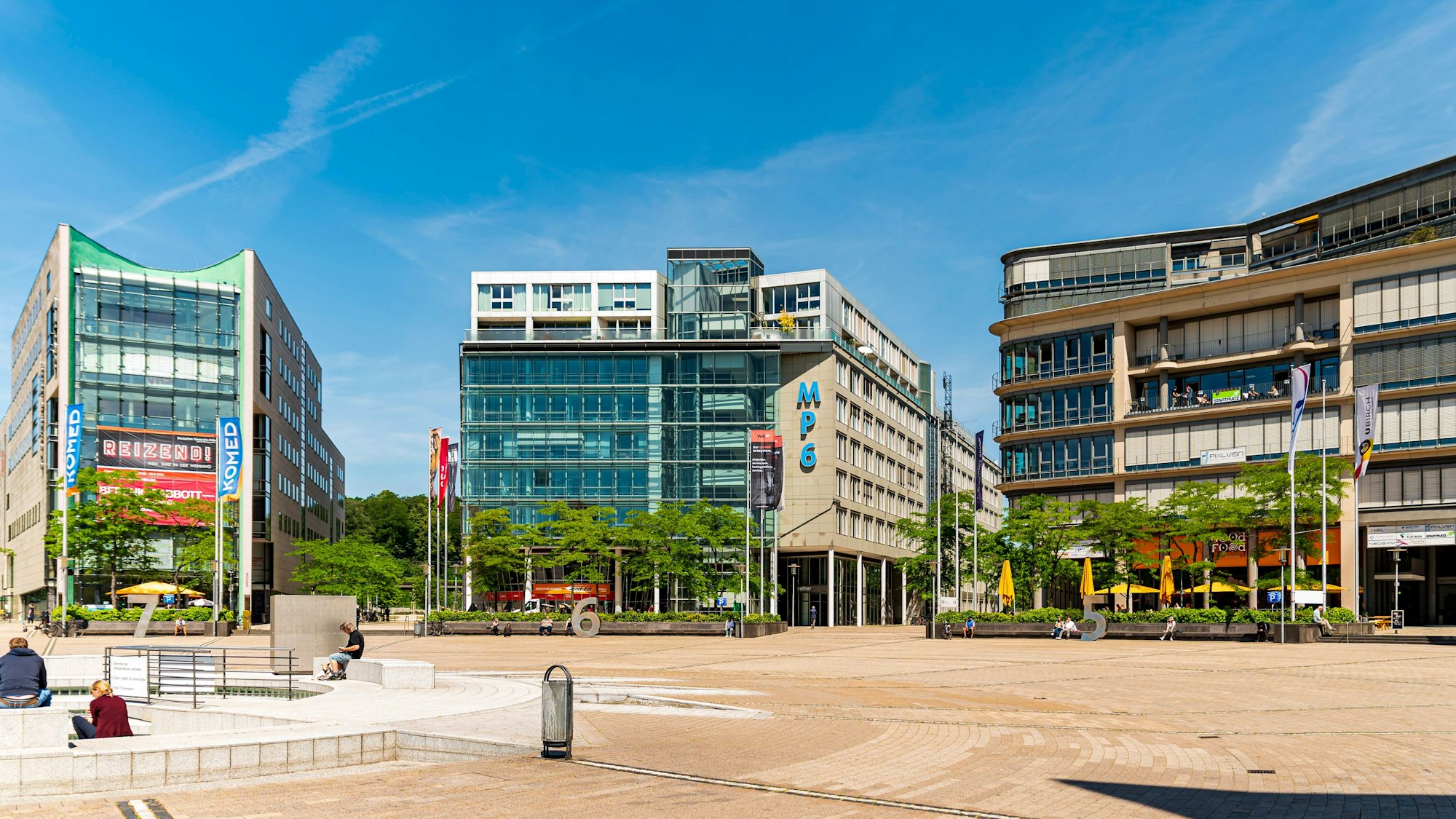 Um einen Platz herum stehen drei Gebäude.