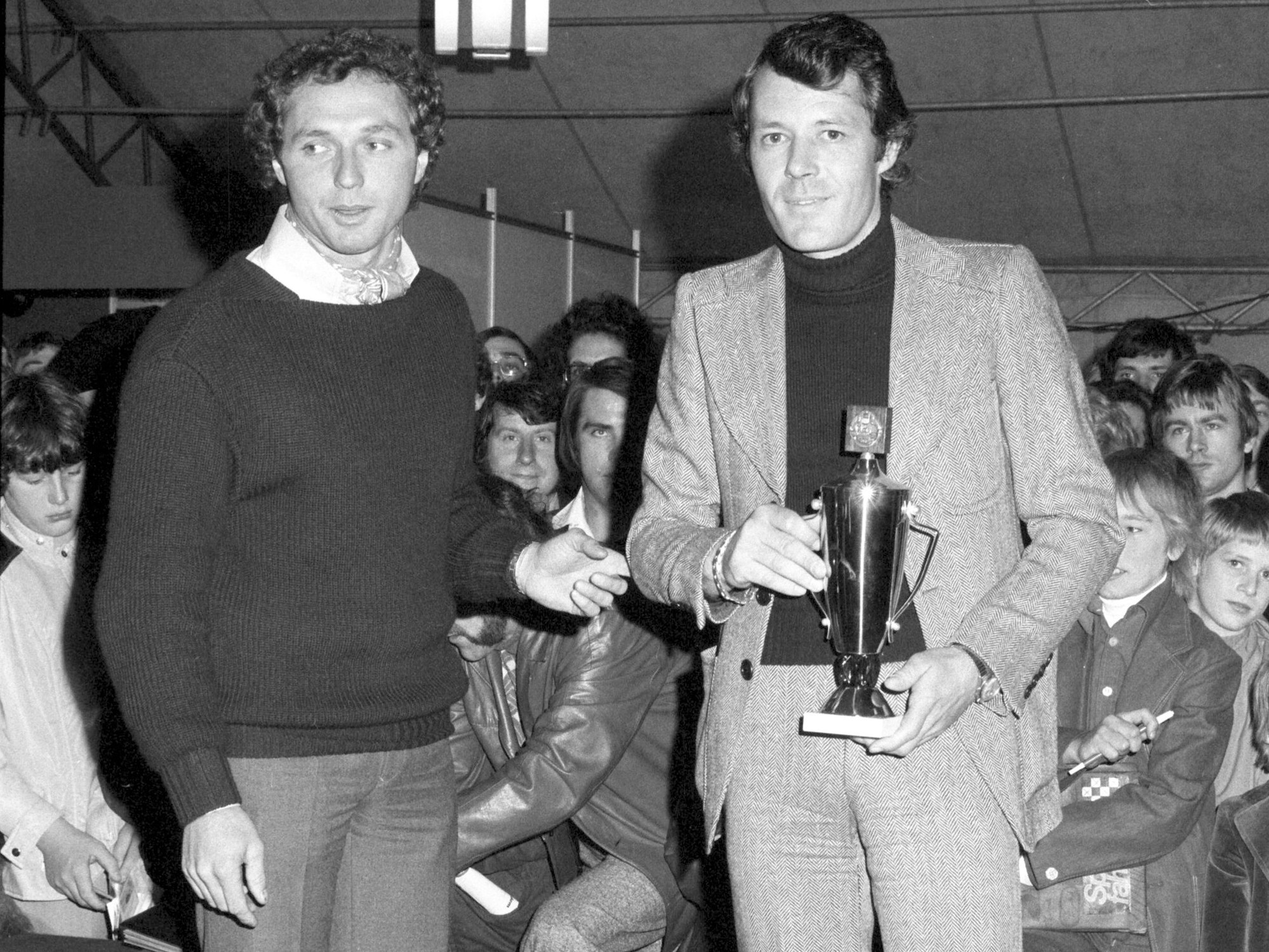 Jochen Mass und Moderator Rainer Braun bei einer Rennwagenausstellung 1975 in Köln.