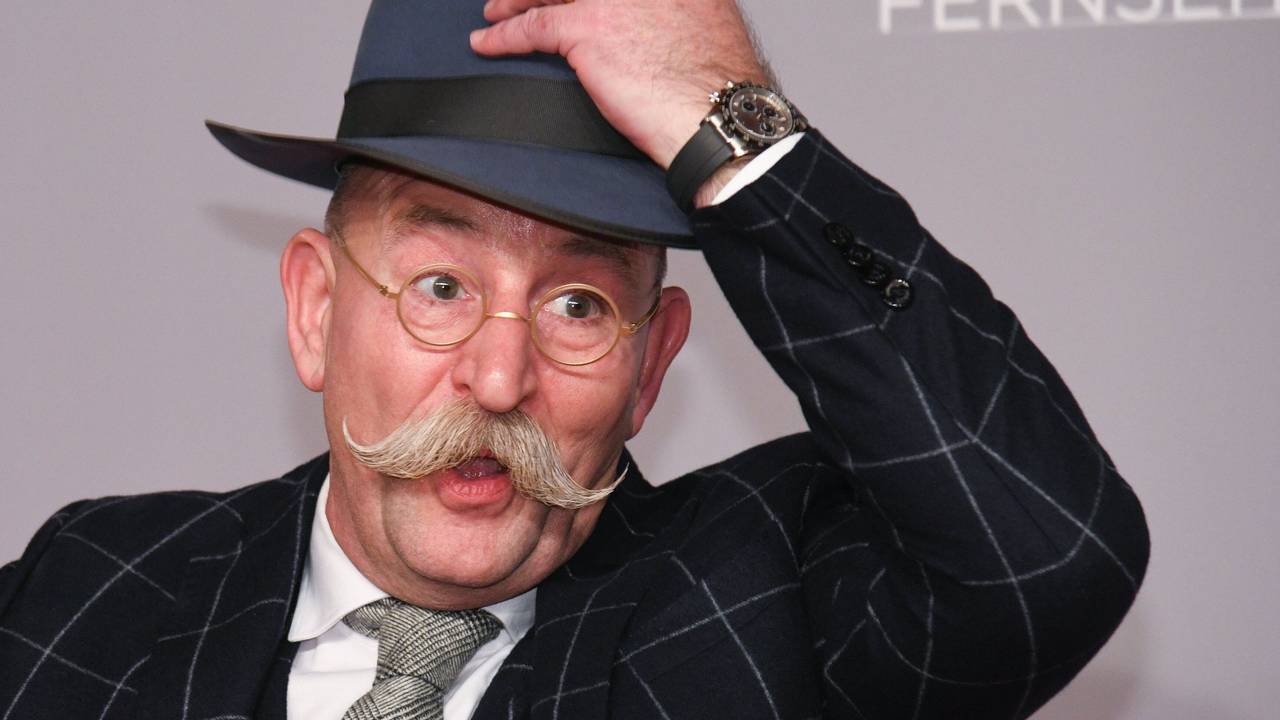 Horst Lichter, Fernsehkoch und Moderator, steht bei der Verleihung des Deutschen Fernsehpreises vor einer Wand und lüftet seinen Hut.