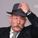 Horst Lichter, Fernsehkoch und Moderator, steht bei der Verleihung des Deutschen Fernsehpreises vor einer Wand und lüftet seinen Hut.