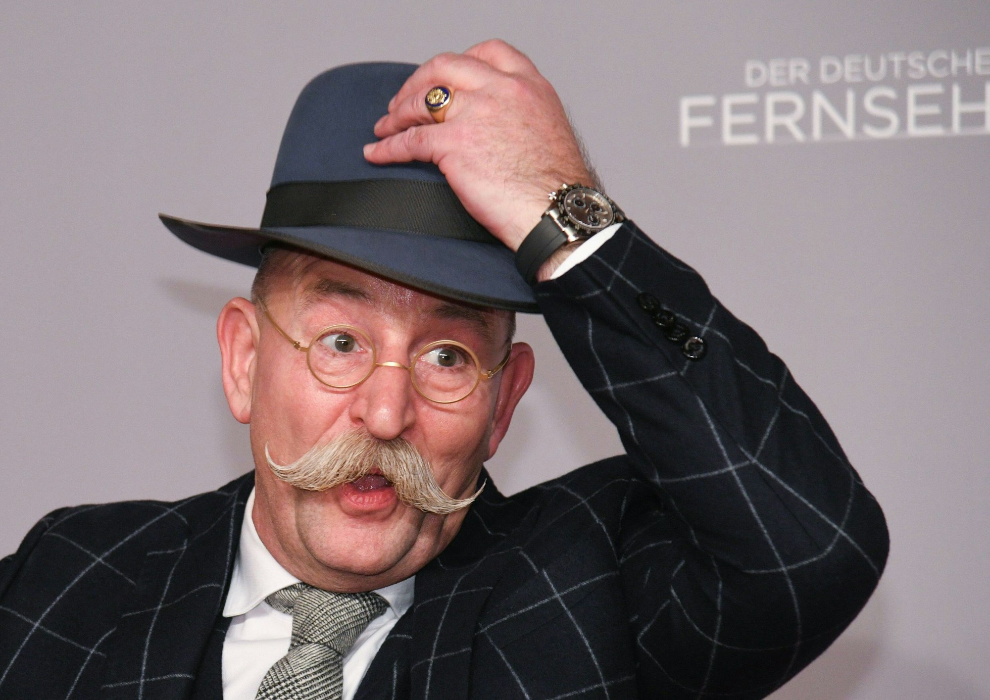 Horst Lichter, Fernsehkoch und Moderator, steht bei der Verleihung des Deutschen Fernsehpreises vor einer Wand und lüftet seinen Hut.