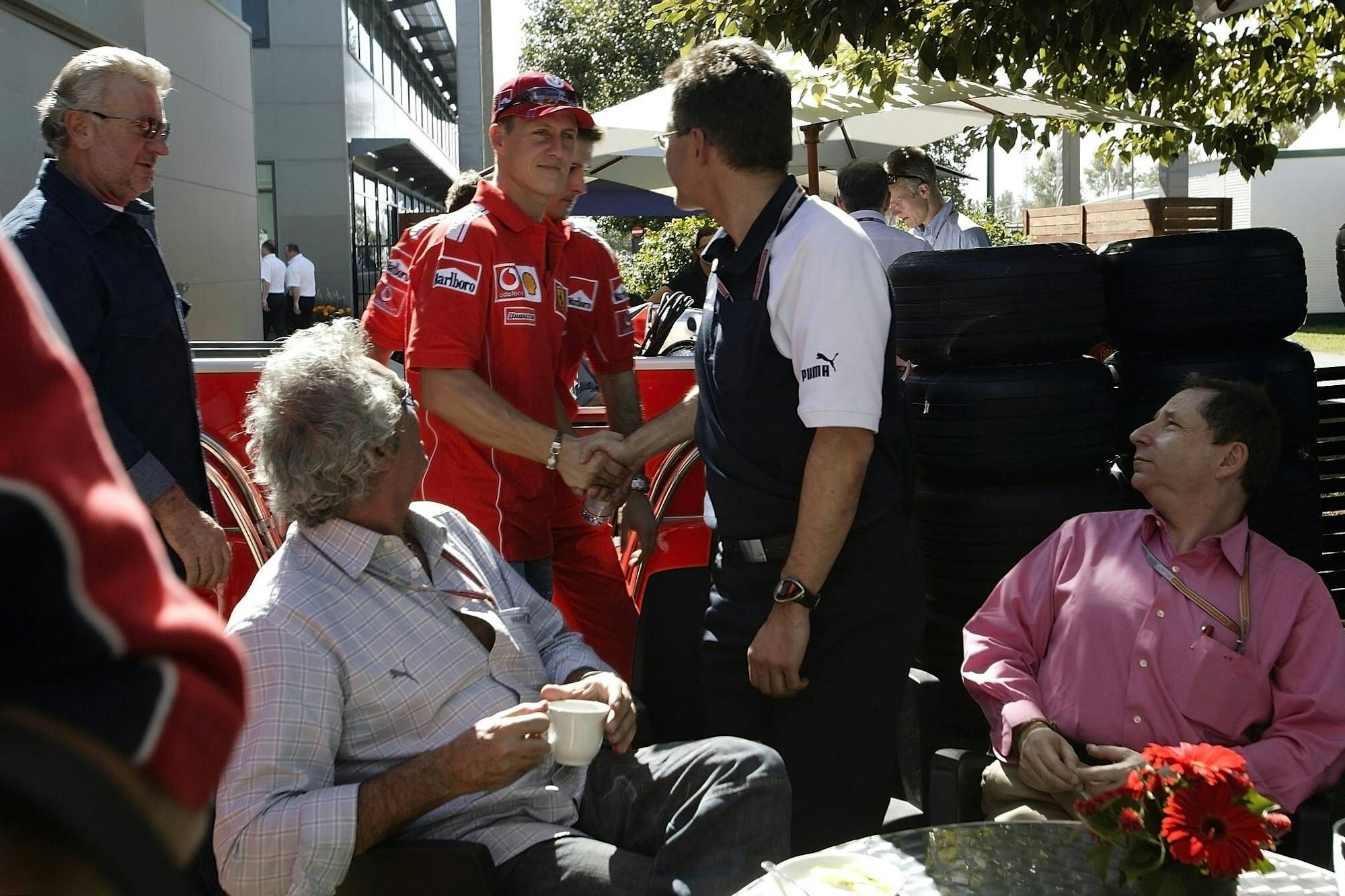 Flavio Briatore und Jean Todt schauen zu, als Schumi Dr. Mario Theißen die Hand schüttelt.