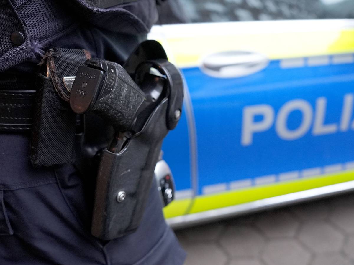 Eine Schusswaffe im Halfter vor einem Polizeiauto.