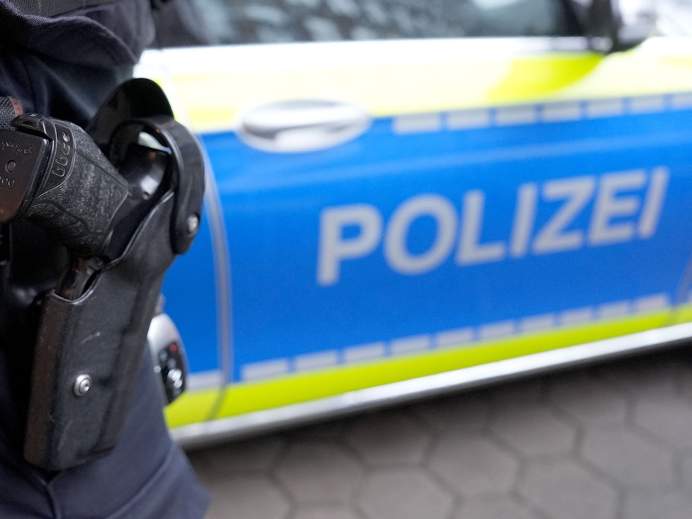 Eine Schusswaffe im Halfter vor einem Polizeiauto.