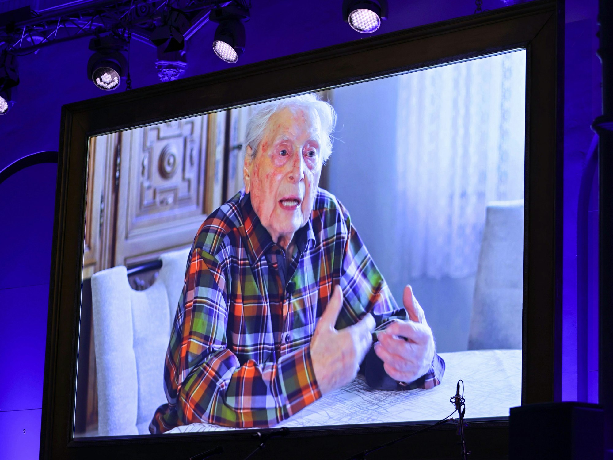 Ludwig Sebus wird von der Videoleinwand eingespielt.