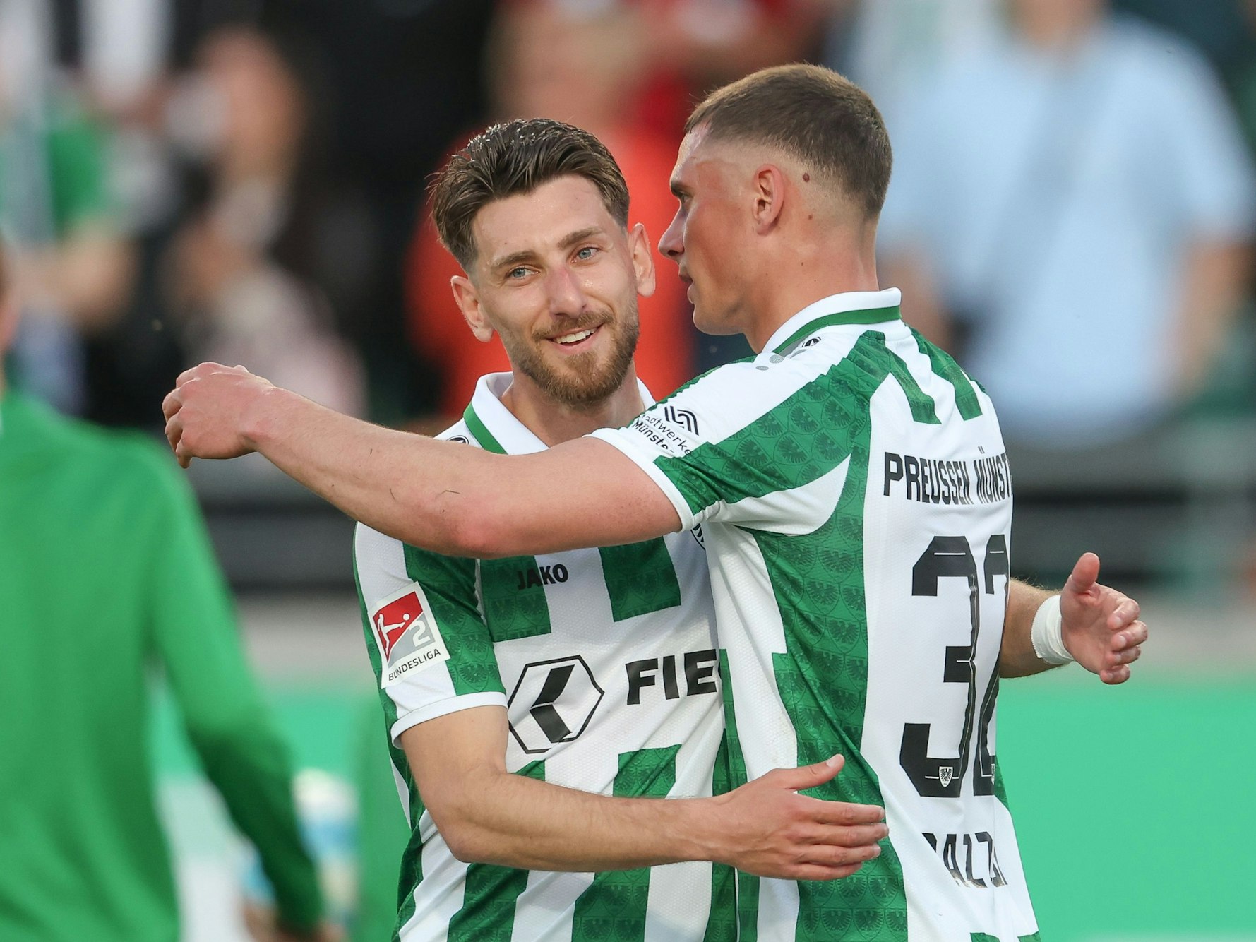 Haralambos Makridis (l) und Luca Bazzoli freuen sich über den Sieg von Preußen Münster gegen Hertha BSC.