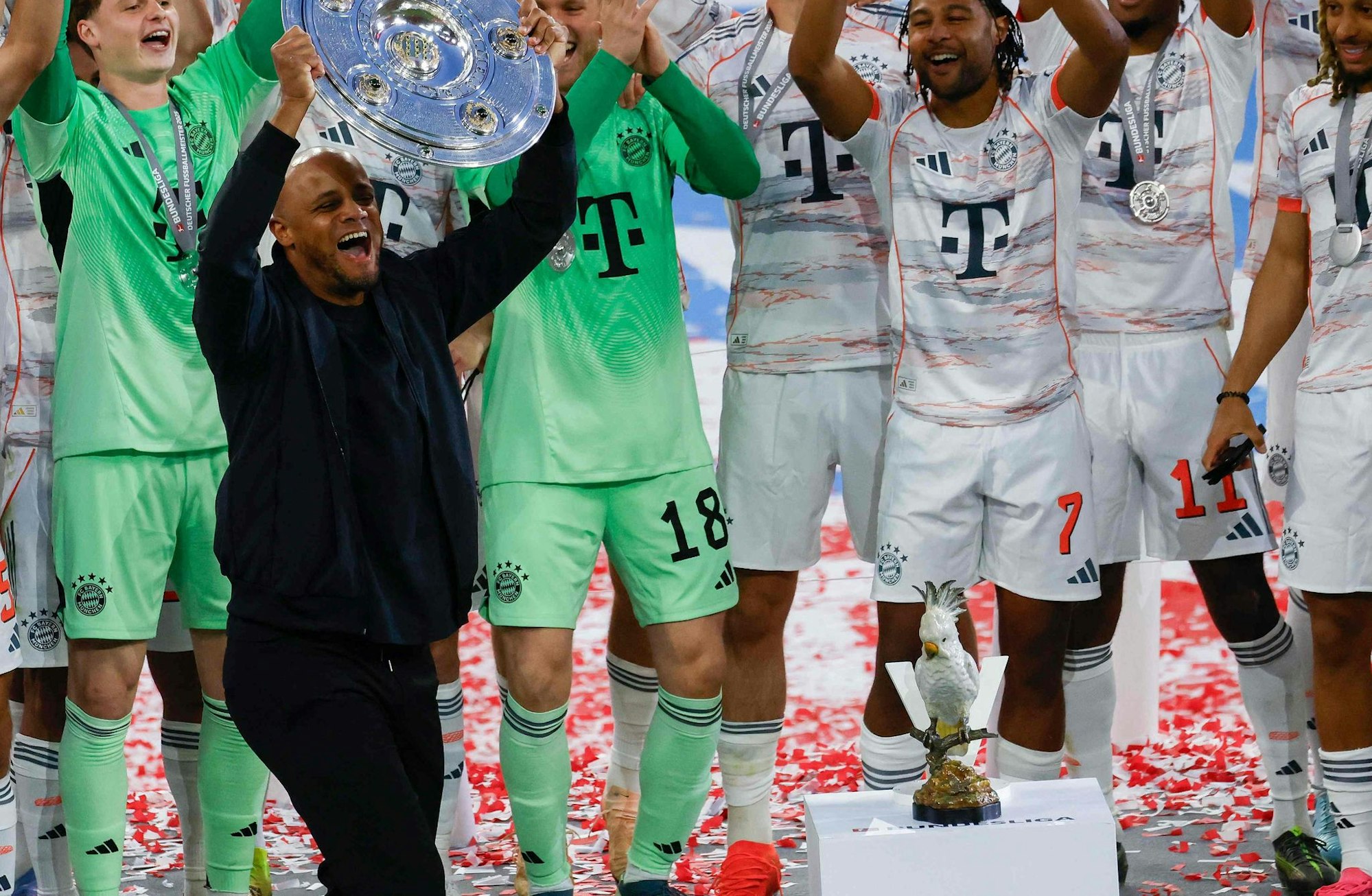 Trainer Vincent Kompany mit der Schale – ganz in der Nähe der von ihm mit auf die Bühne gebrachten Figur eines Kakadu.