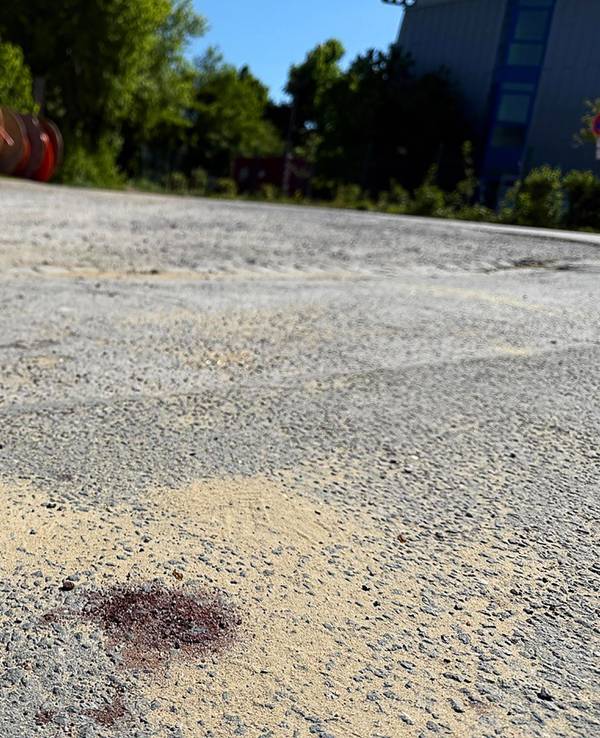 Ein Blutfleck ist auf dem Asphalt am Tatort in Menden im Sauerland zu sehen. Nach dem gewaltsamen Tod eines 14-Jährigen ermittelt die Polizei.