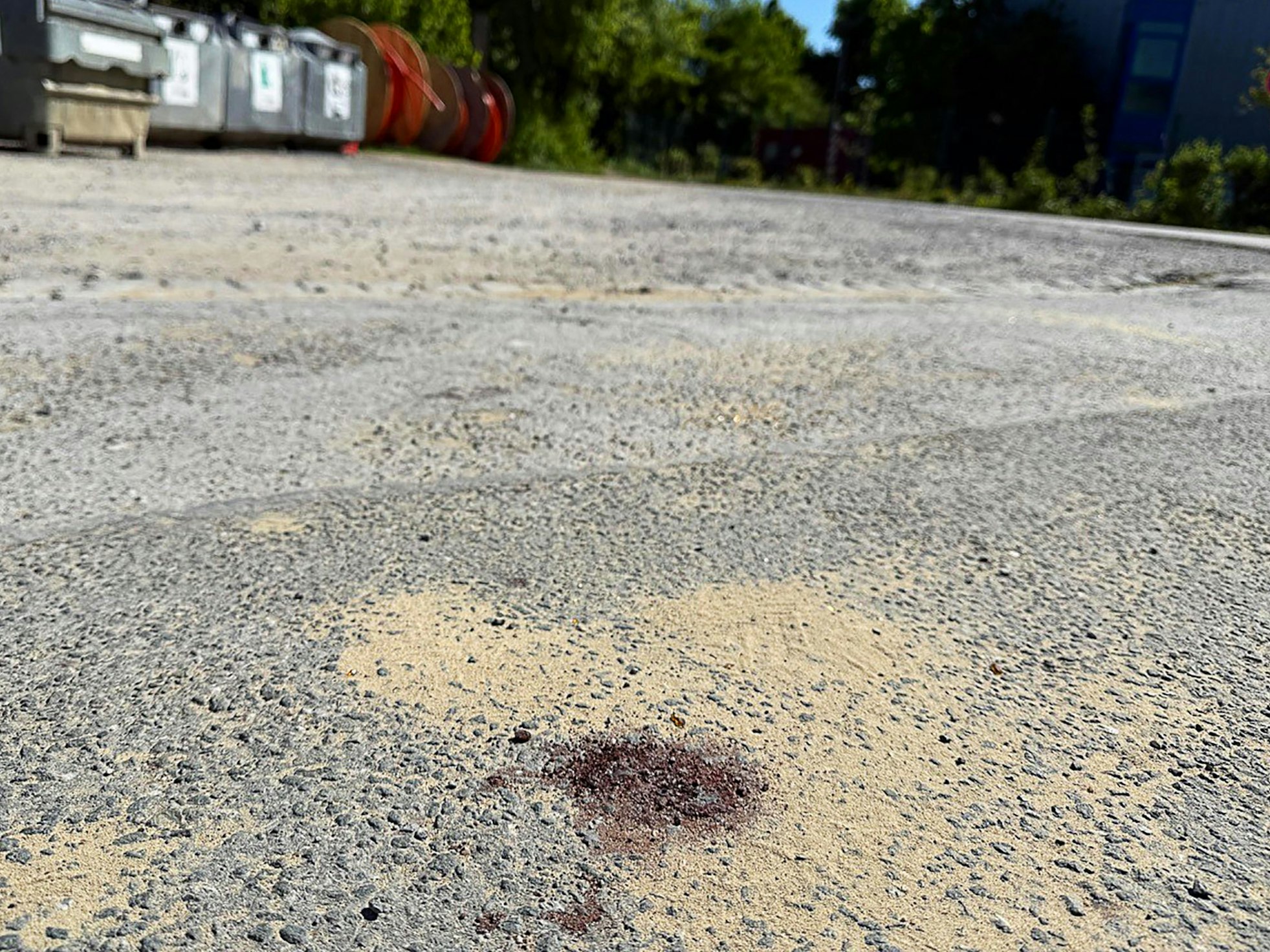 Ein Blutfleck ist auf dem Asphalt am Tatort in Menden im Sauerland zu sehen. Nach dem gewaltsamen Tod eines 14-Jährigen ermittelt die Polizei.