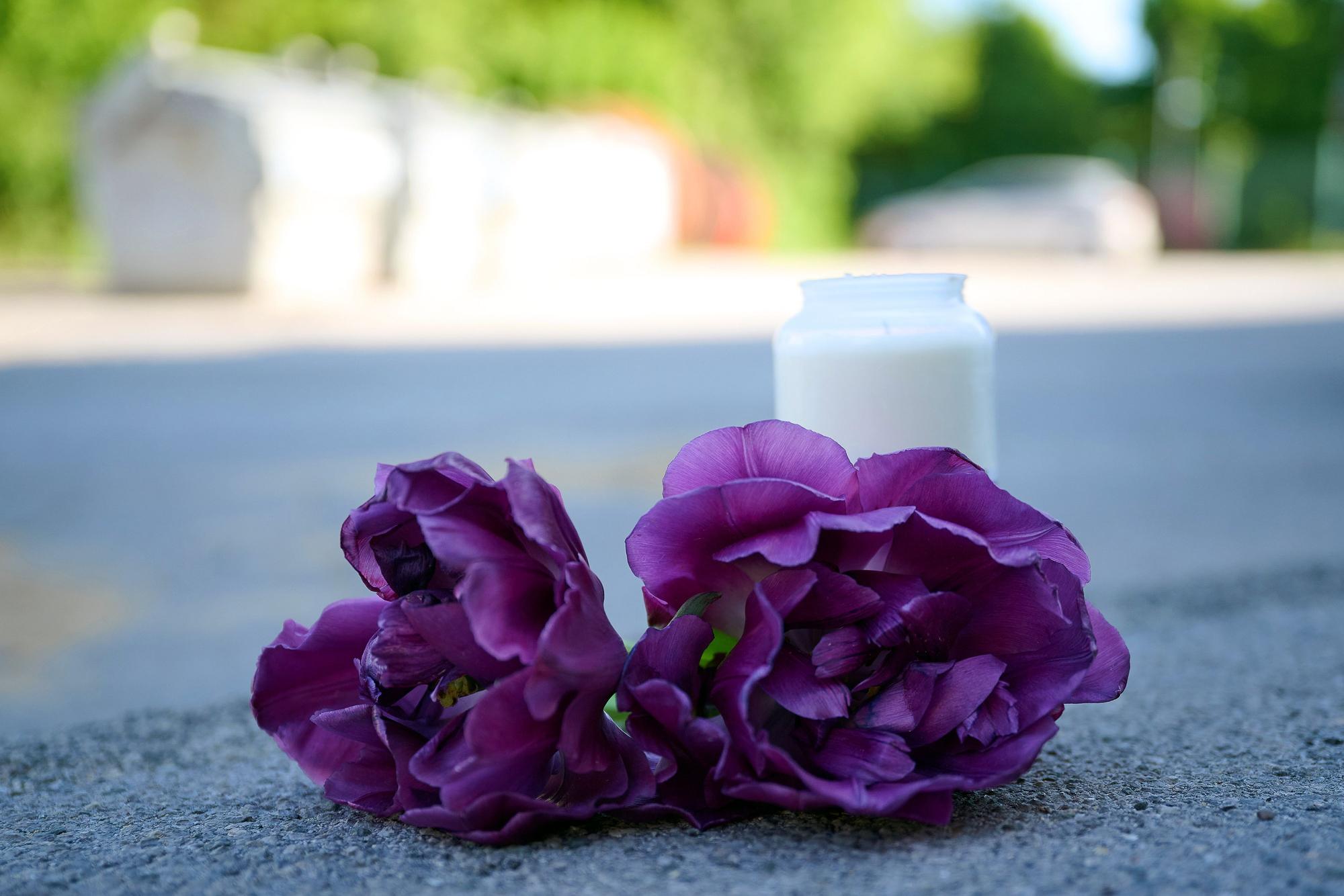 Blumen und eine Kerze liegen auf einem Schotterplatz vor dem Eingang zu einem Spielplatz.